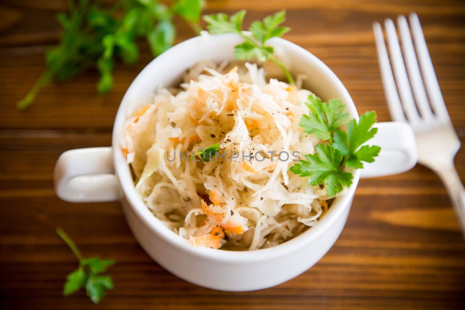 sauerkraut with carrots and spices in a bowl on a wooden table.