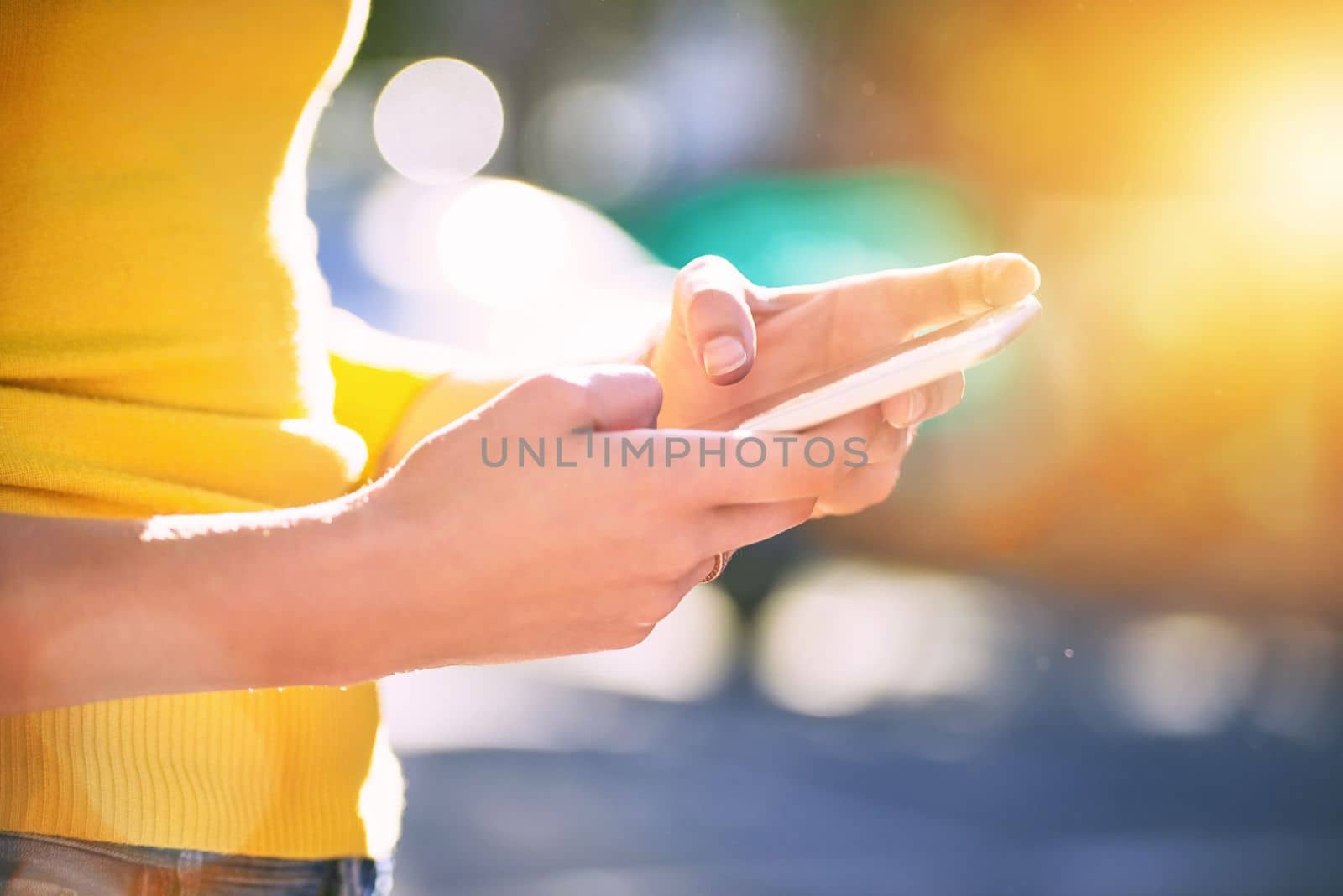 Instant communication in a fast paced world. an unrecognizable young woman using a smartphone outside. by YuriArcurs