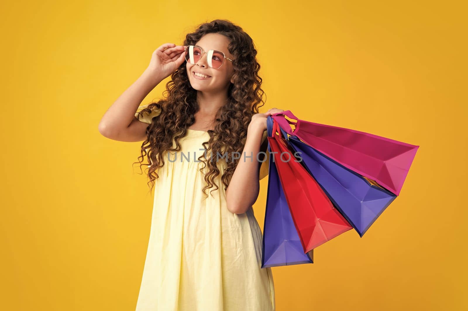 Happy teenager portrait. Funny teen girl hold shopping bag enjoying sale isolated on yellow. Portrait of teenager schoolgirl is ready to go shopping. Smiling girl. by RedFoxStudio