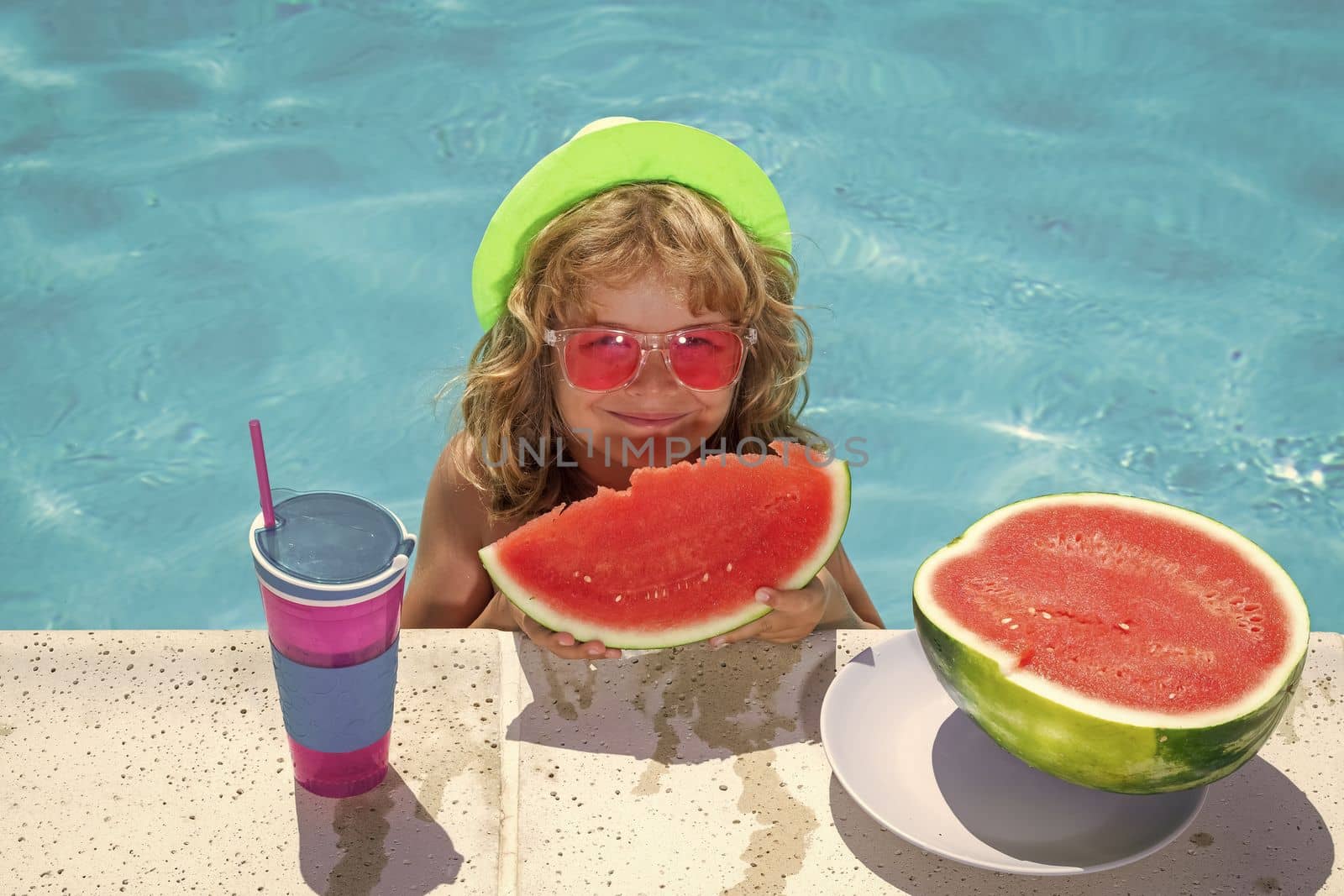 Kid boy eat watermelon in swimming pool. Summer vacation concept. Summer kids portrait with watermelon in pool water