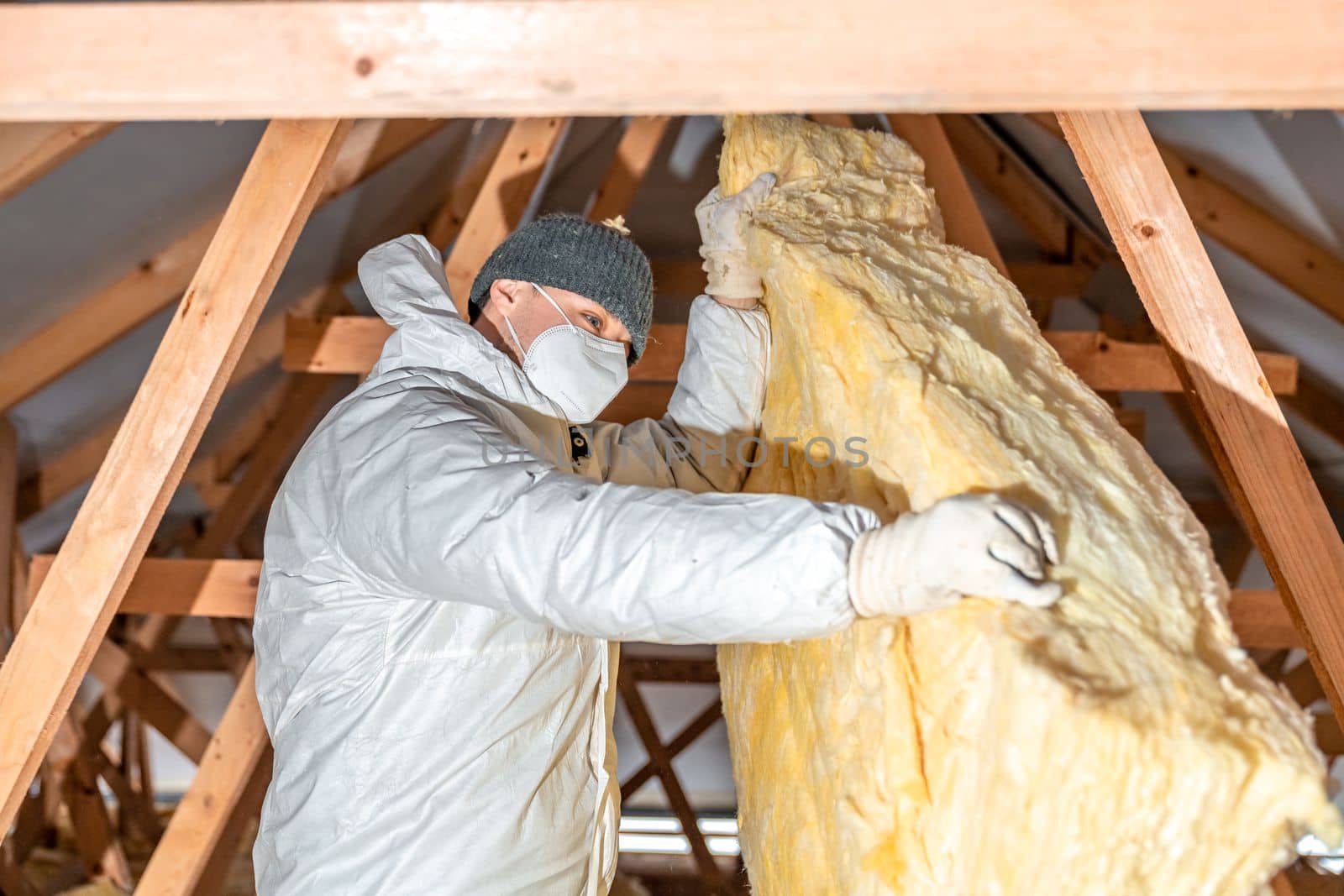 a man insulates the roof and ceiling of the house with glass wool