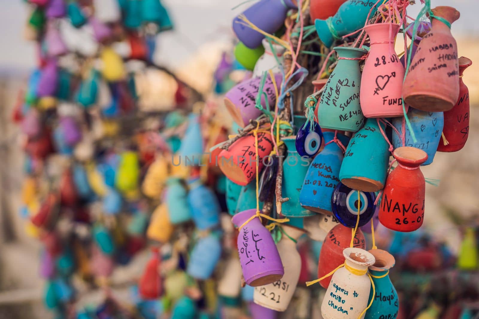 Wish tree. Small multi-colored jugs with inscriptions, wishes hanging on the branches of a tree., against the backdrop of sand ruins and blue sky.
