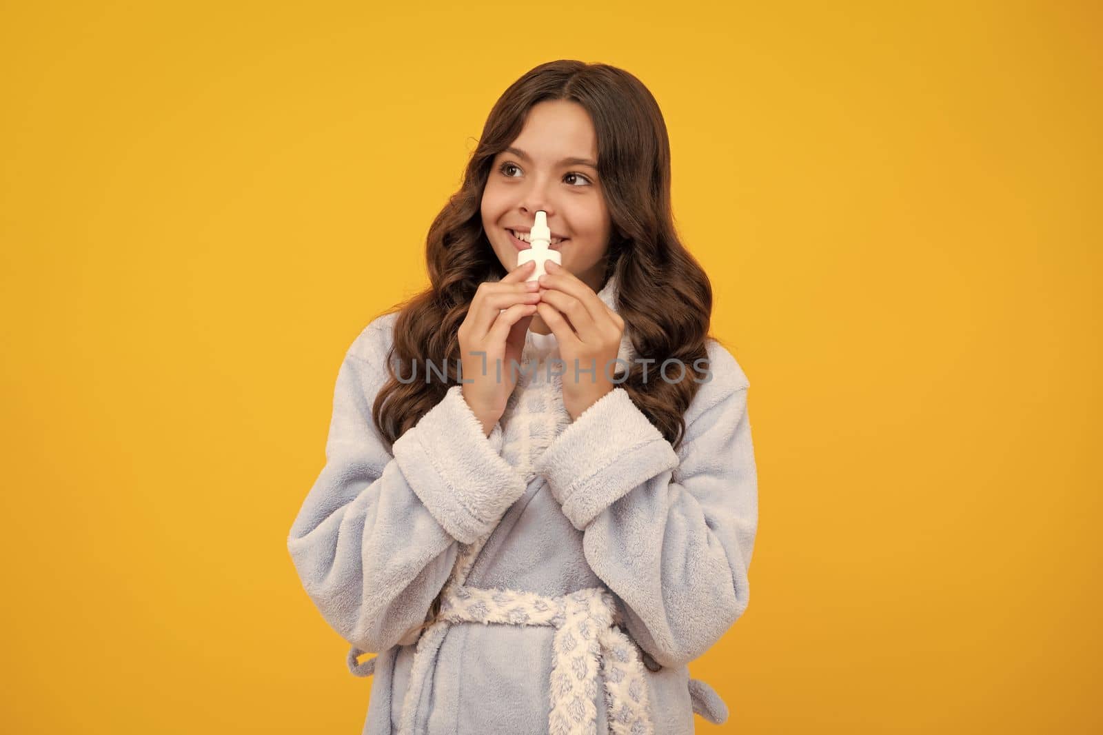 Girl hold medicine nasal spray from running nose, virus pandemic. Sick teen girl with nasal spray on yellow background