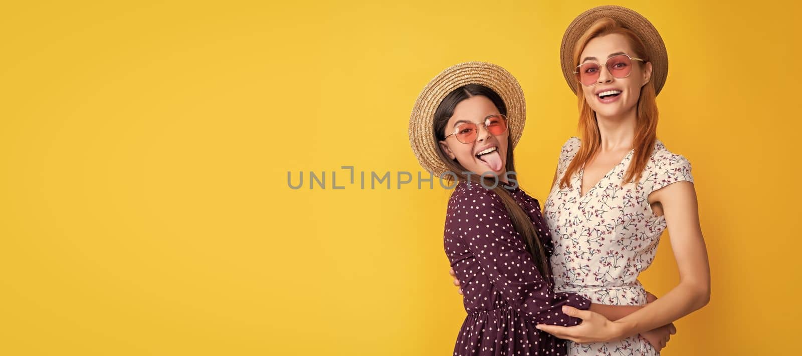 Mother and daughter kid banner, copy space, isolated background. glad mom and daughter in straw hat on yellow background