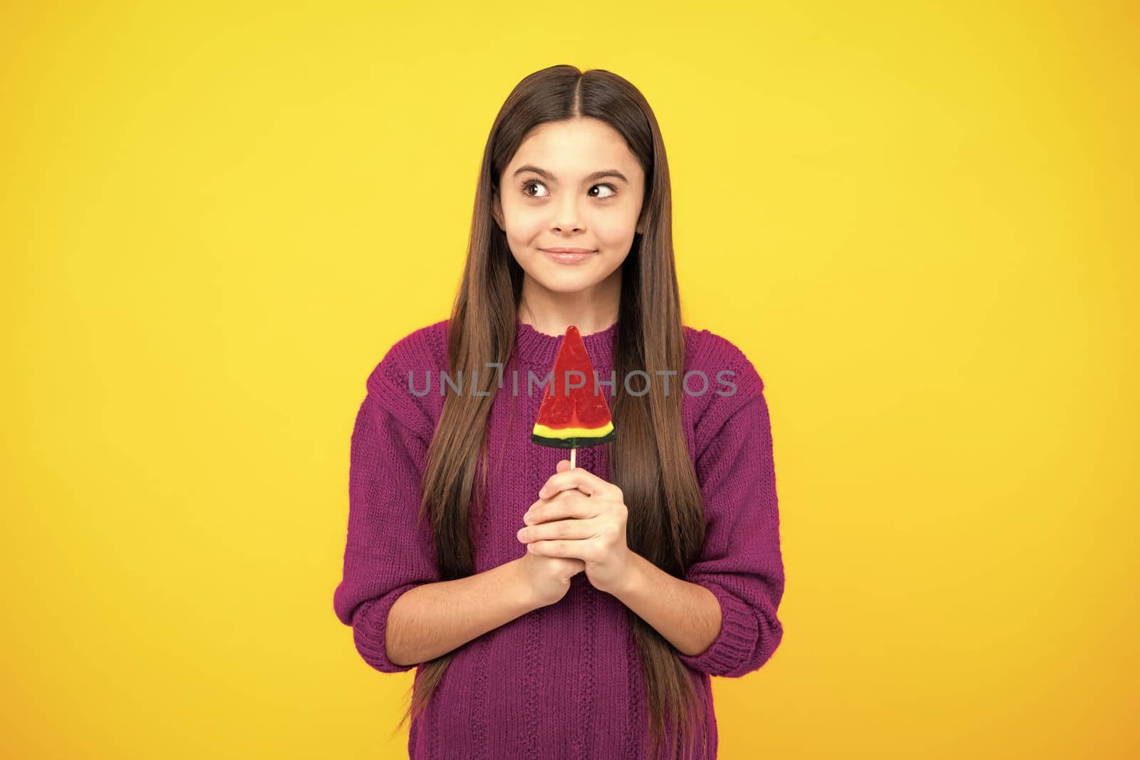 Teen girl hold lollipop caramel on yellow background, candy shop. Teenager with sweets suckers. by RedFoxStudio