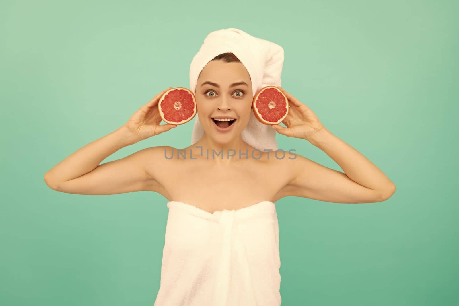 shocked young woman in towel after shower with grapefruit on blue background by RedFoxStudio