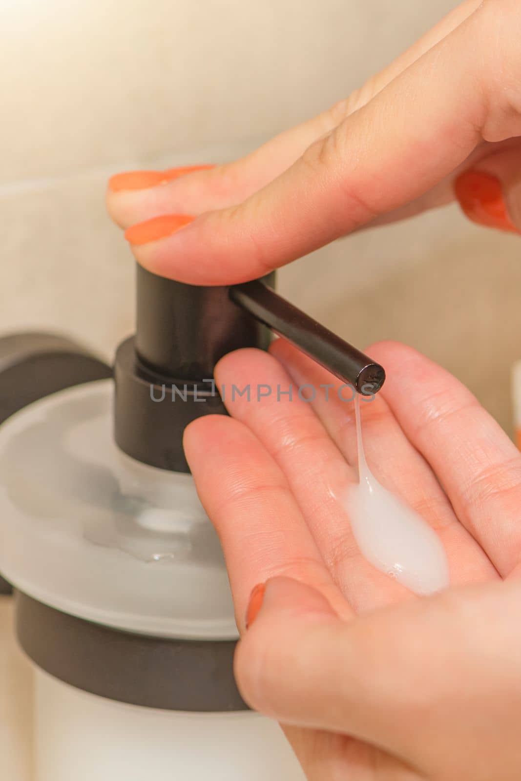 Washing and disinfecting hands, a woman uses liquid soap to wash her hands, in the bathroom, close-up. Place for text or copy space.