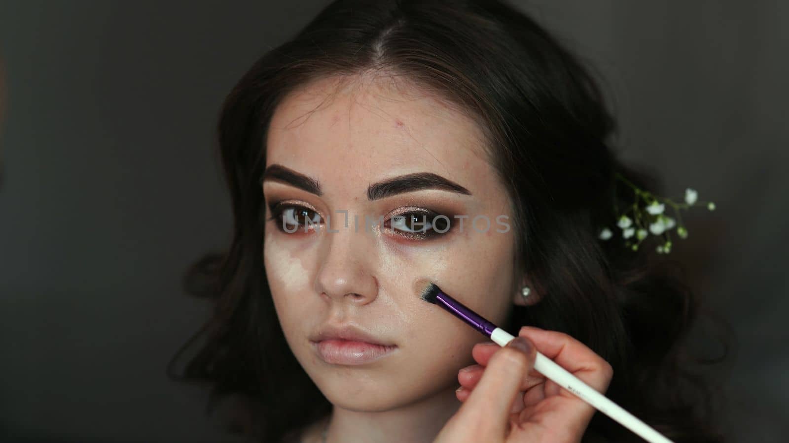 Makeup artist applies foundation on the face of the model