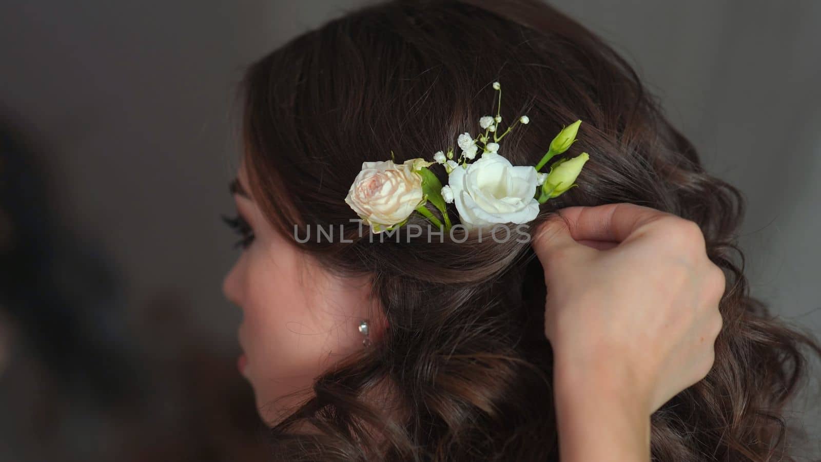 The stylist adorns the girl's hair with delicate flowers