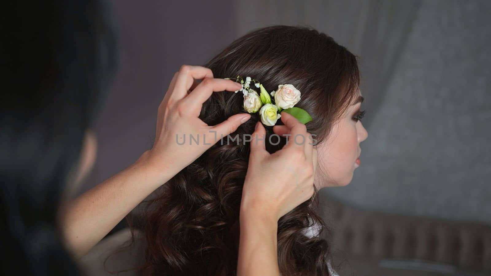 The stylist adorns the girl's hair with delicate flowers