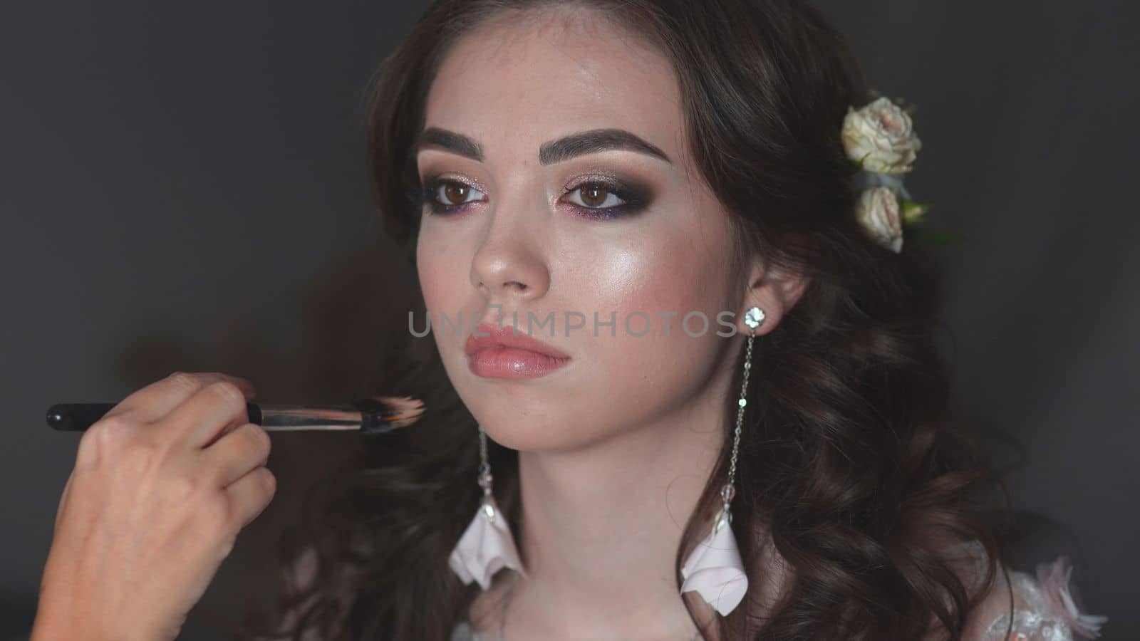 Girl make-up artist applies powder on the face of the model