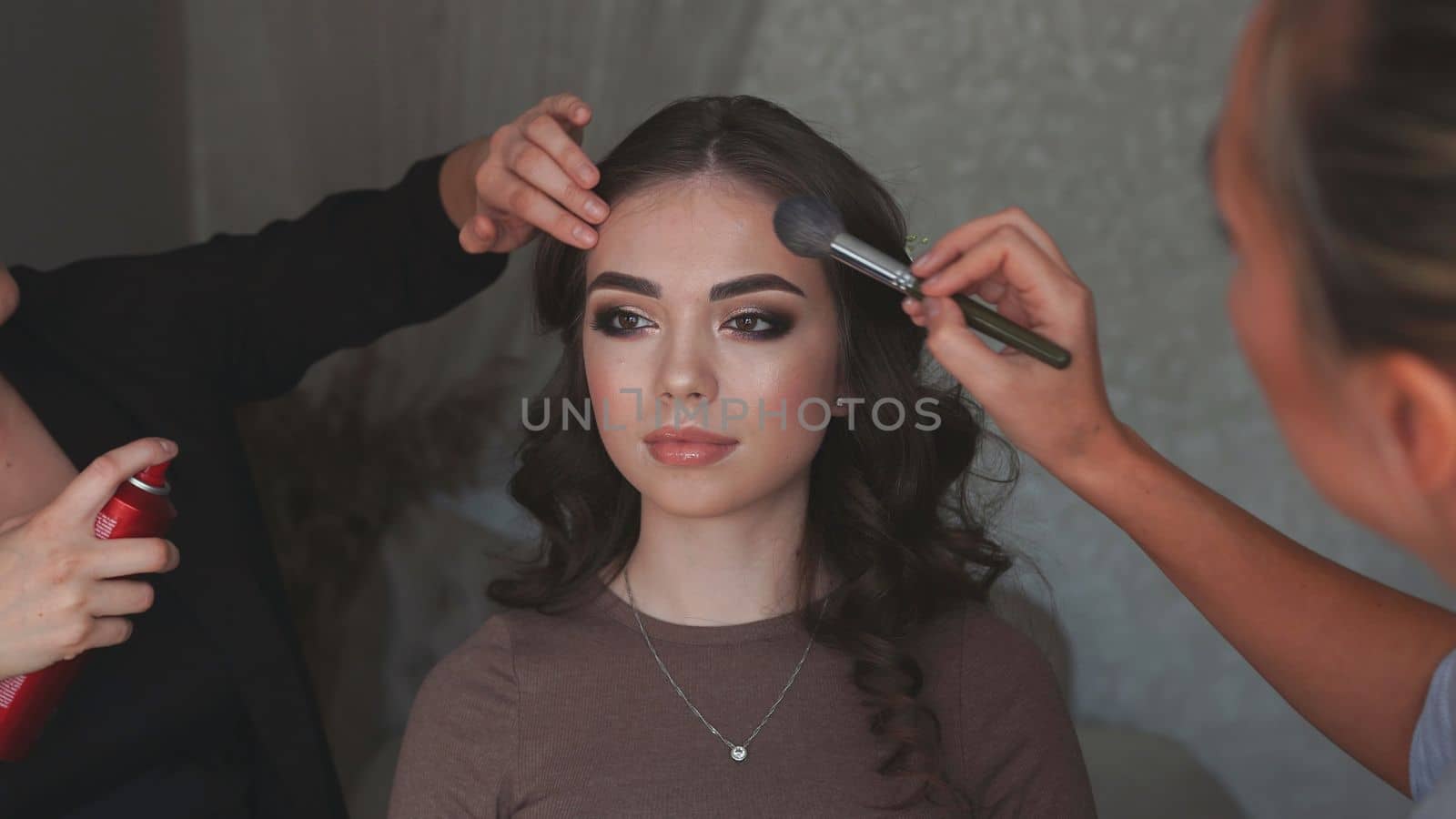 Makeup artist and hairdresser work on the image of the model