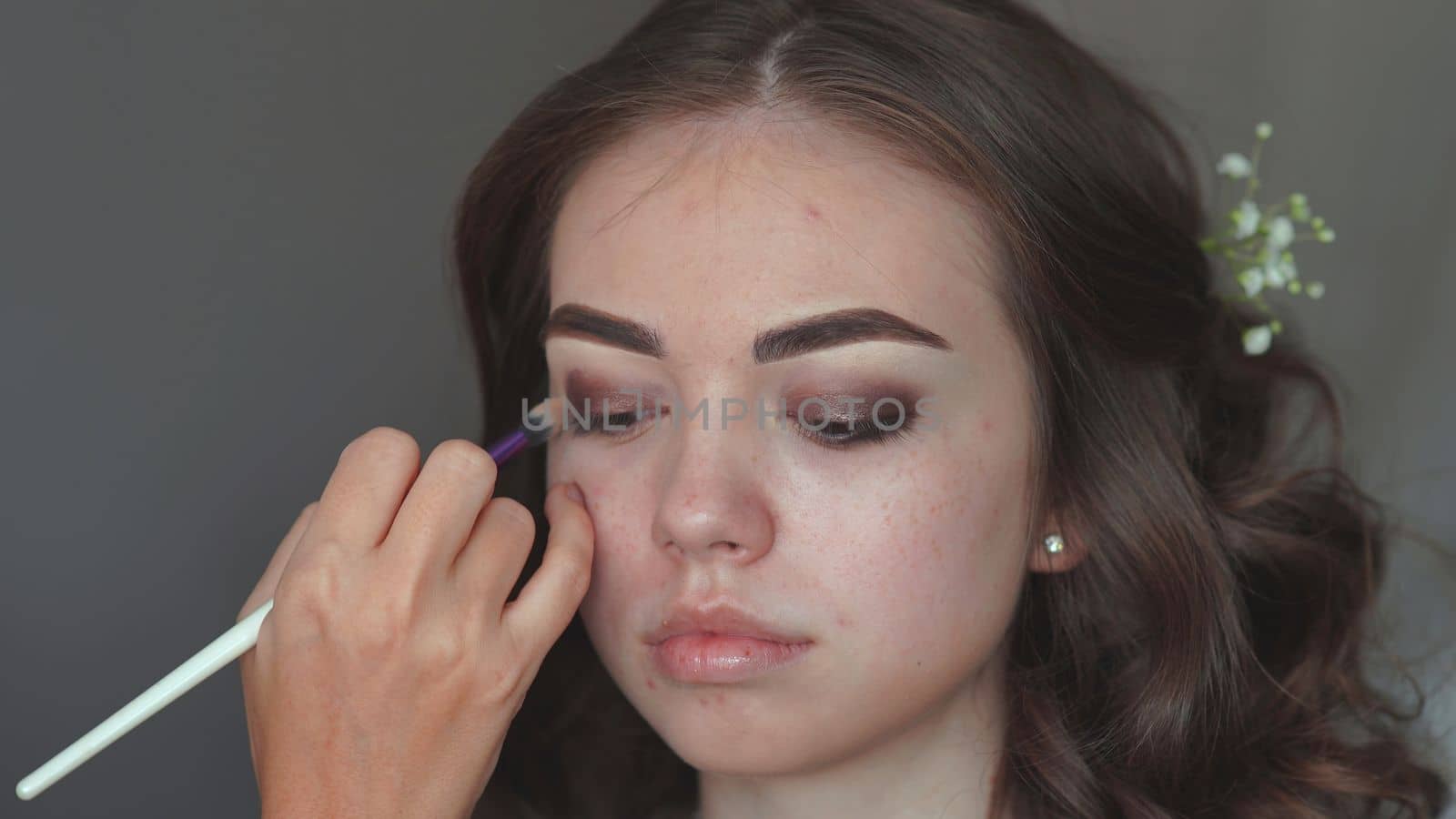Makeup artist paints the eyelids of a girl model. by DovidPro