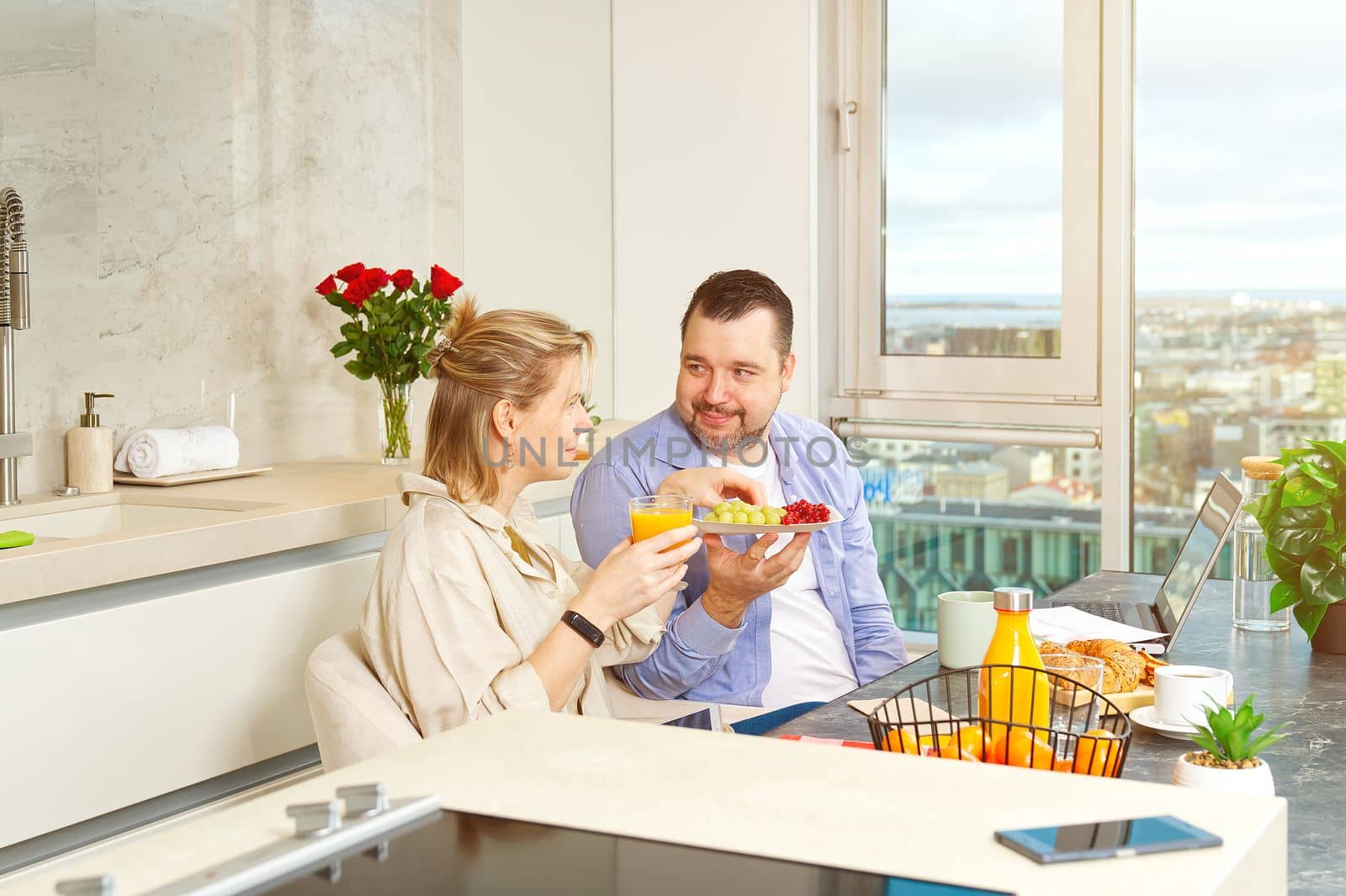 Young beautiful happy couple having breakfast together in kitchen at home. Lifestyle by PhotoTime