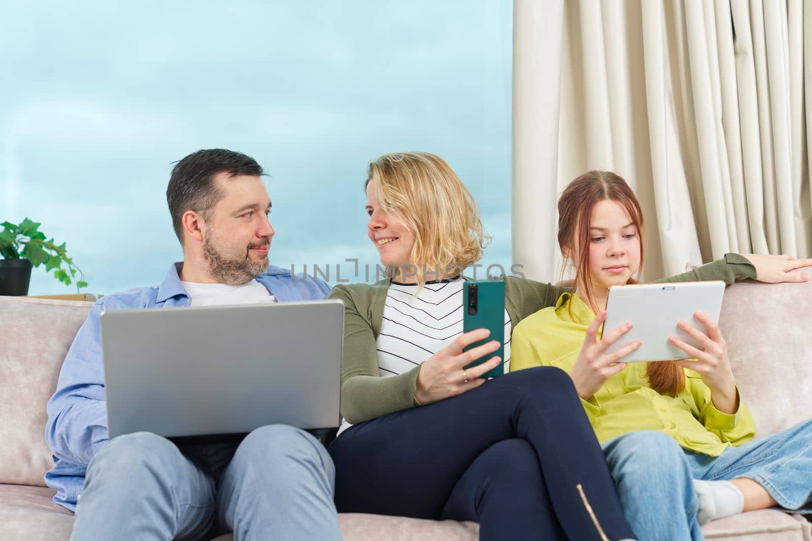 Happy Family on couch using gadget. Rest at home. Using Digital devices at home by PhotoTime