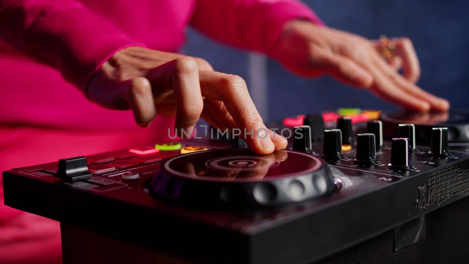 Musician standing at dj table mixing sound using professional mixer console, performing new album during night party in club. Artist enjoying playing music using audio equipment. Close up