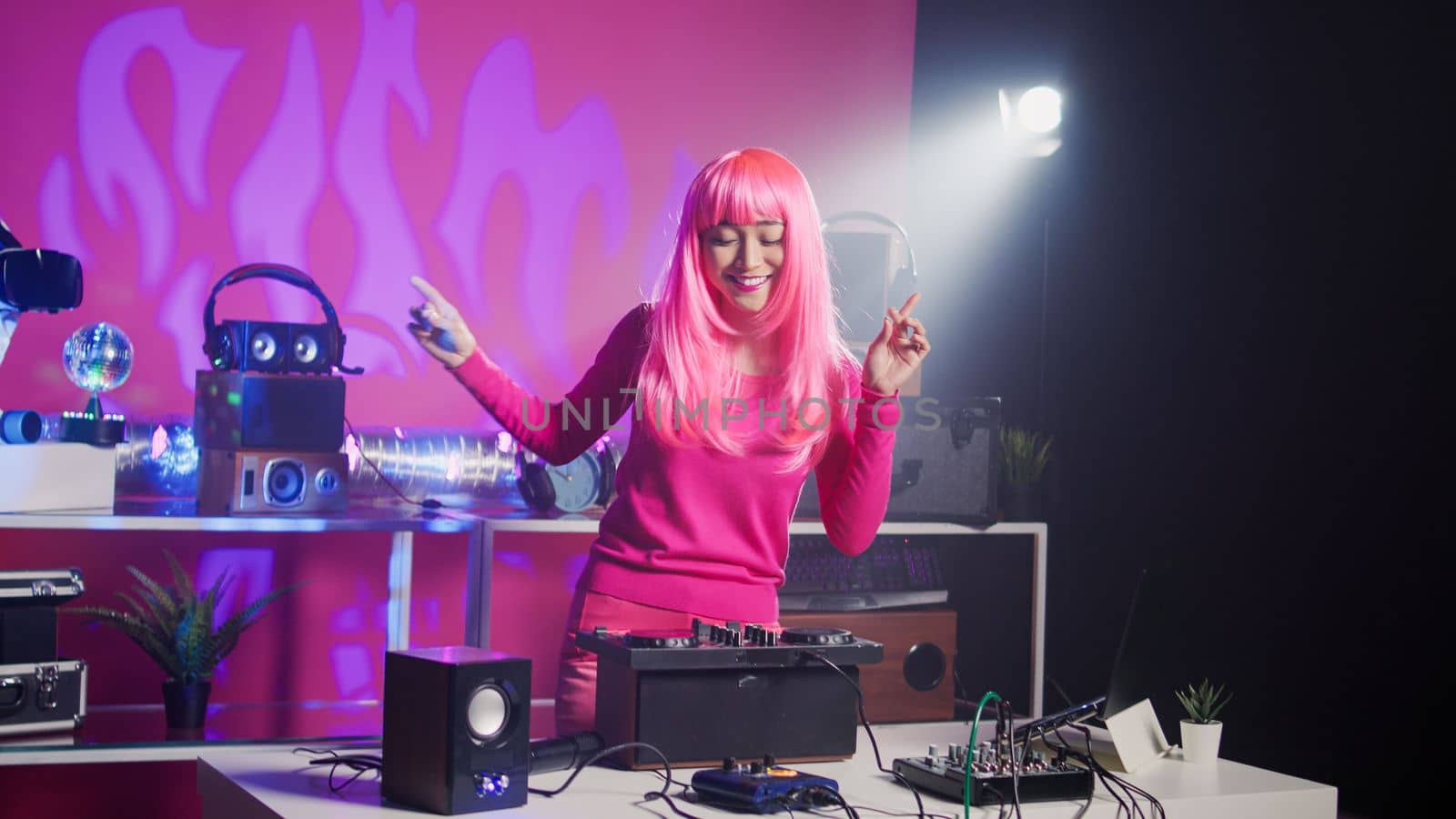 Cheerful dj performing electronic music during concert in nightclub, enjoying dancing and having fun with fans during performance. Asian performer mixing sound using professional mixer console