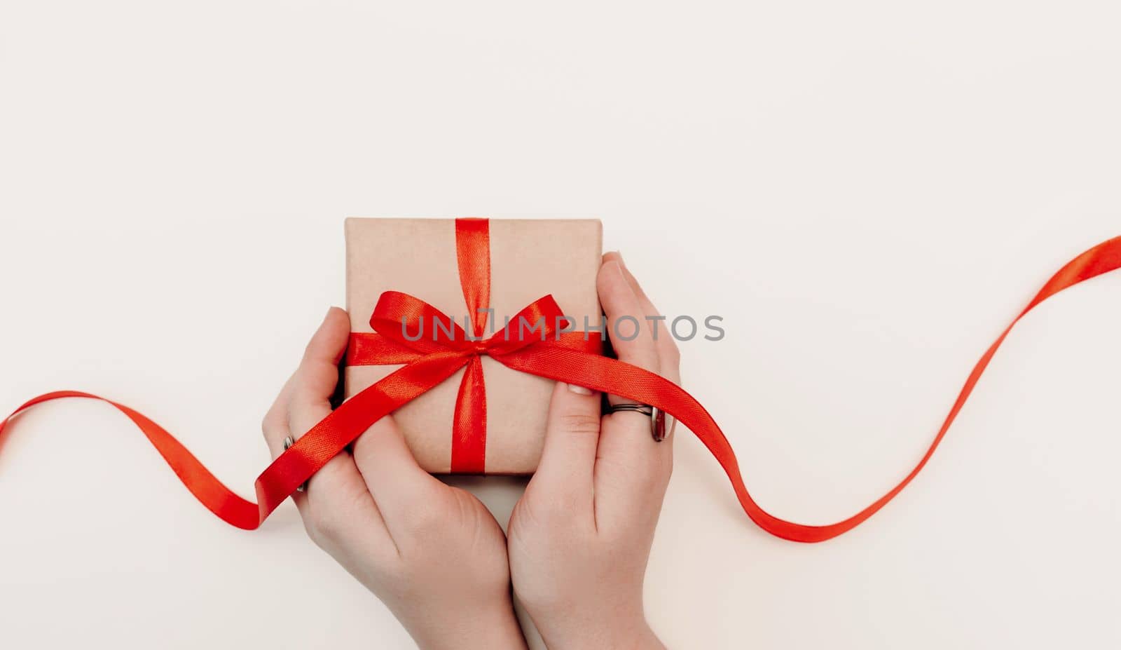 Hand red gift. Women's hands hold a present for christmas or valentine's day. Isolated on white background. View from above by Matiunina