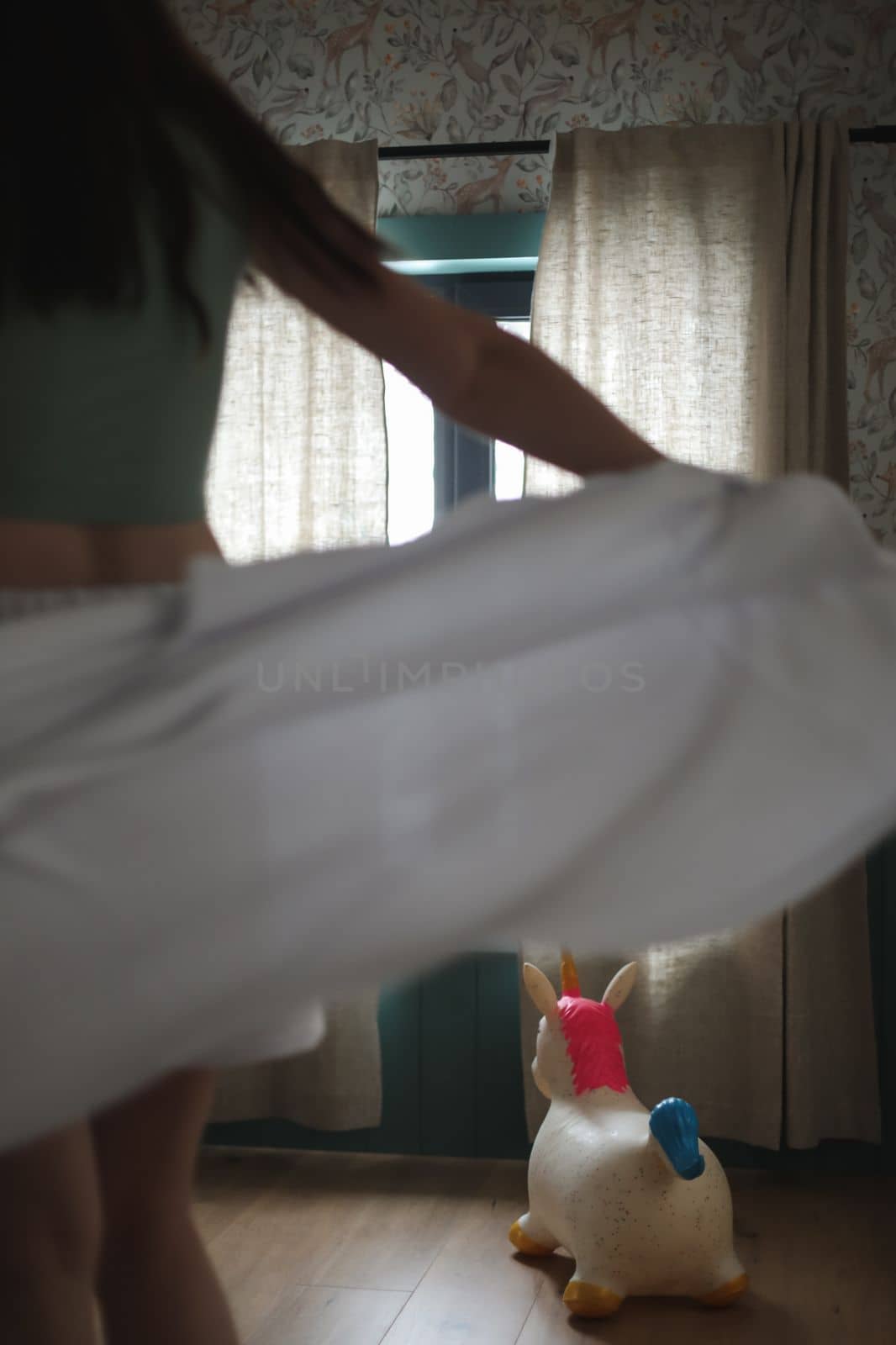 Beautiful woman in white silk pyjama standing near window in a cozy room. emotional portrait.