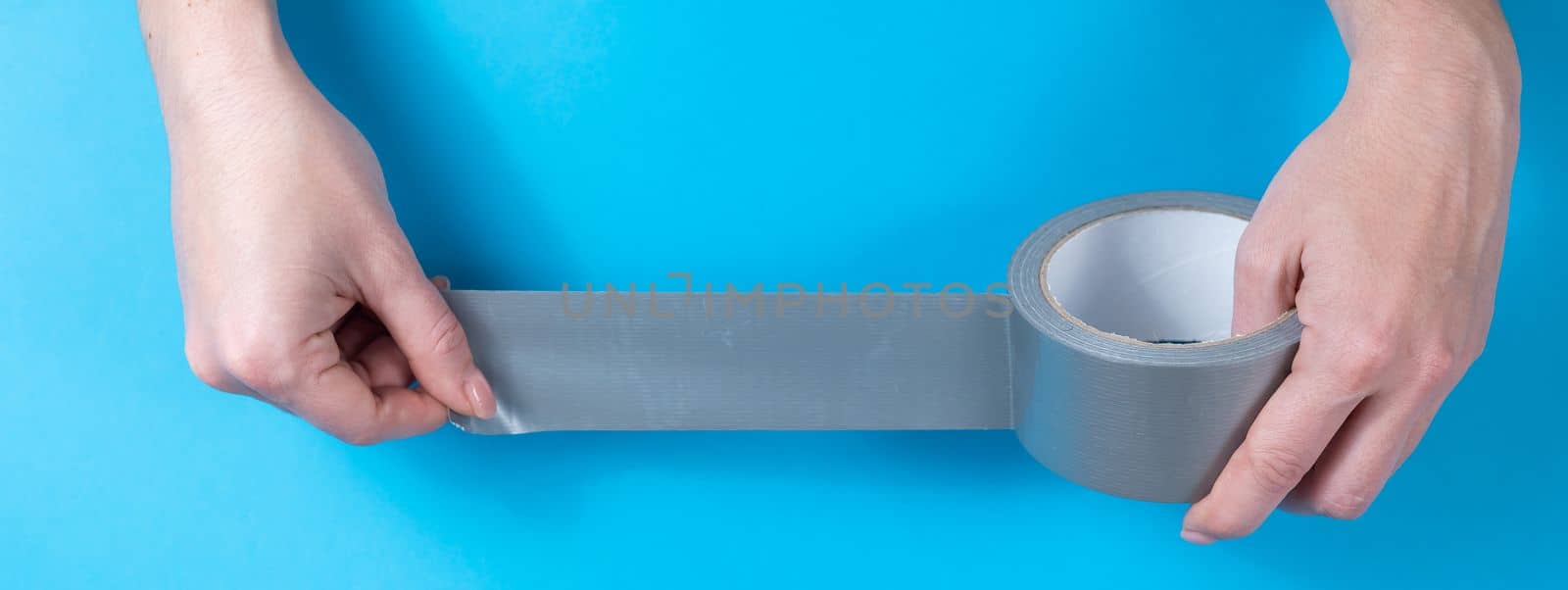 Woman holding silver scotch tape on blue background. by mrwed54