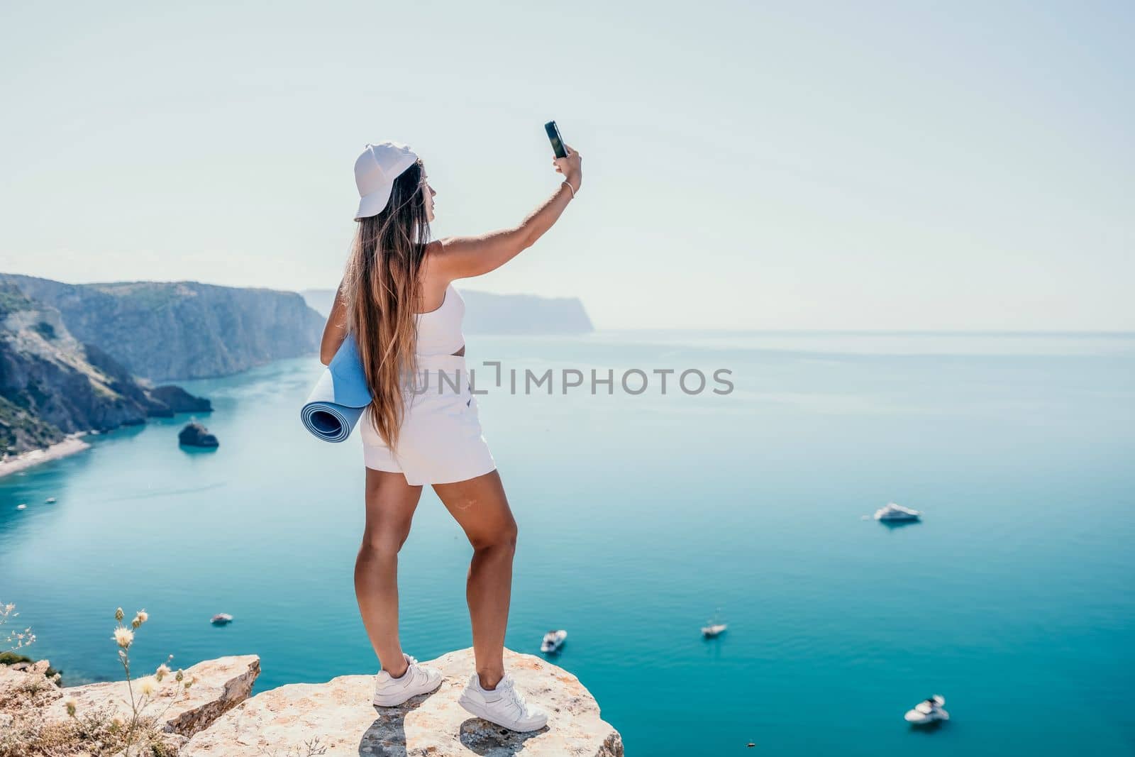 Young woman with black hair, fitness instructor in pink sports leggings and tops, doing pilates on yoga mat with magic pilates ring by the sea on the beach. Female fitness daily yoga concept