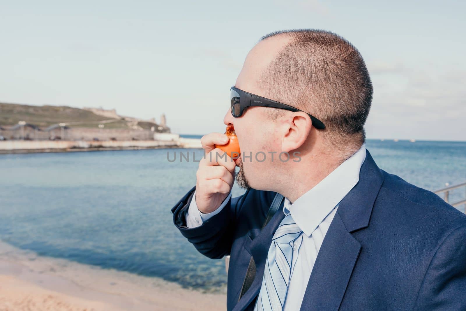 Male persimmon park. Hipster millennial man in a tie and jacket bites off a persimmon while sitting on a park bench in slow motion Young business people eat golden persimmons at lunchtime