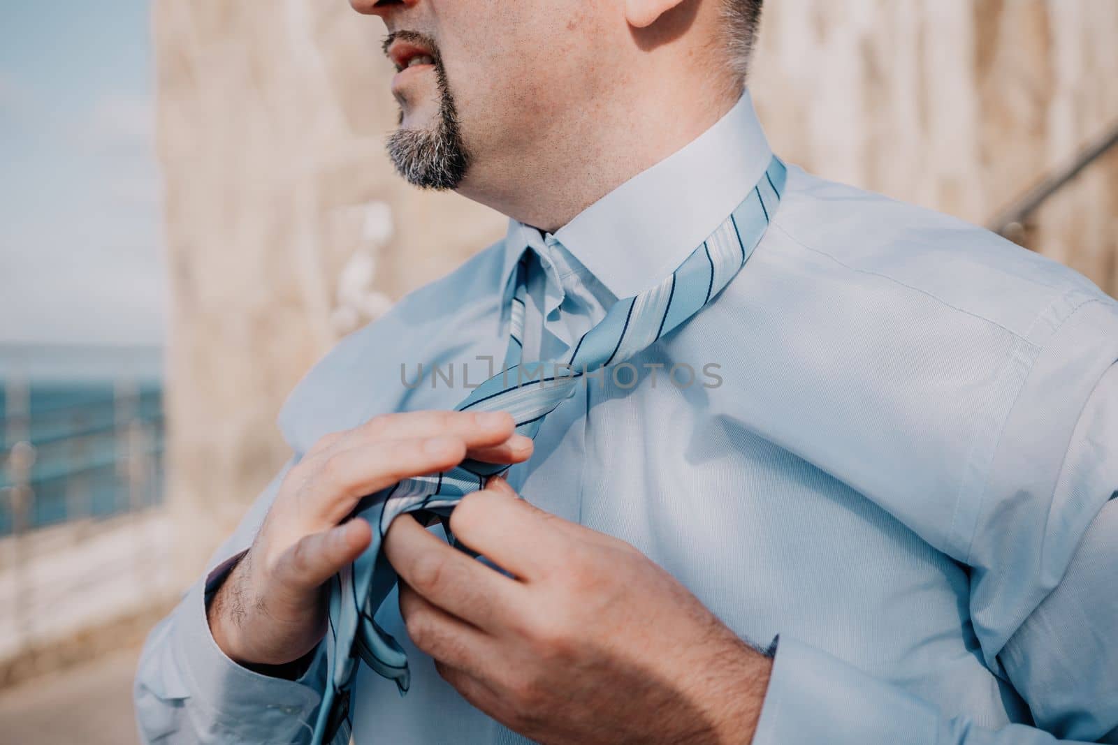 Close up of Man Adjusting Tie of Suit. Businessman in white shirt straightens his tie, close-up.