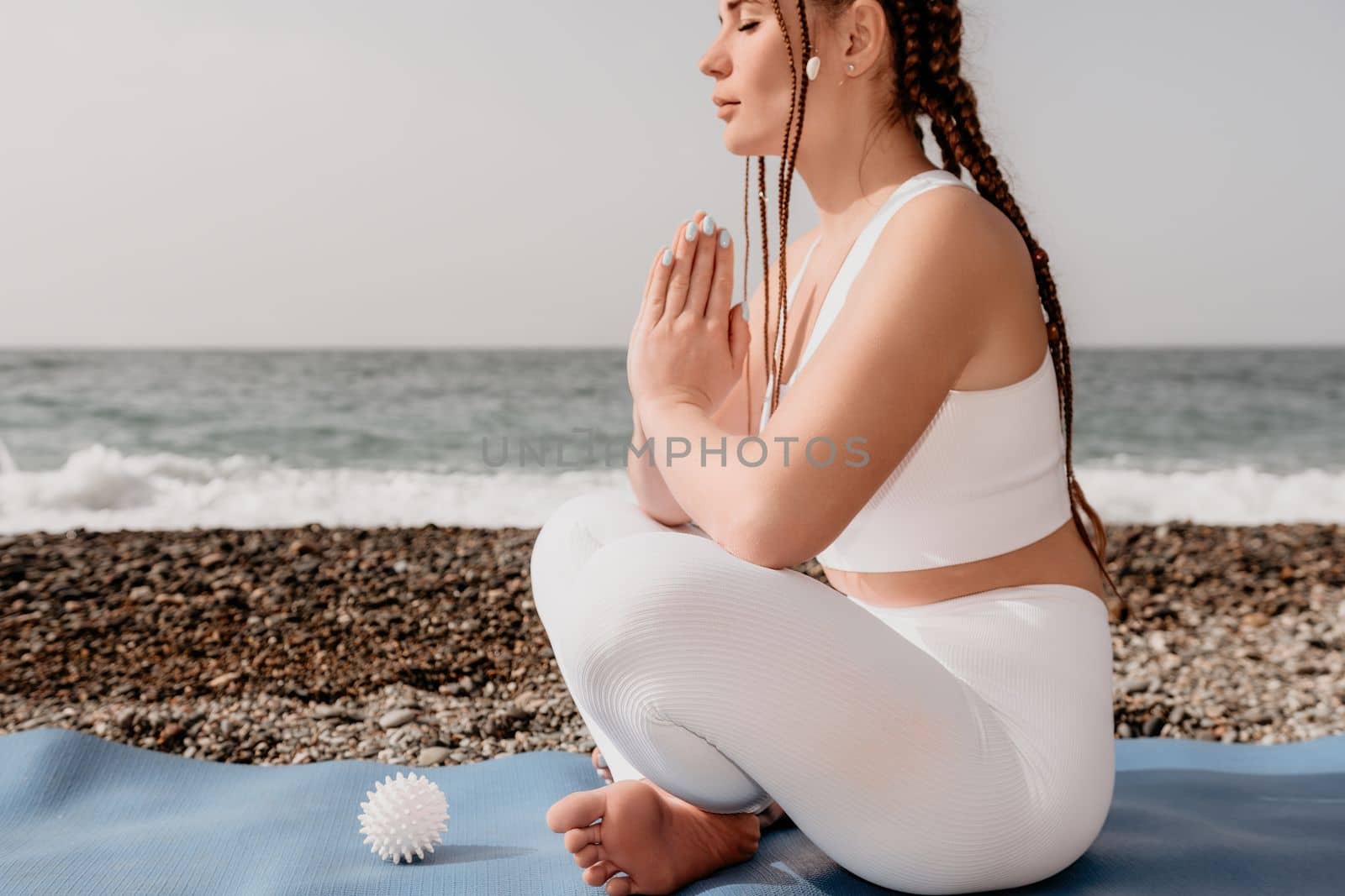 Close up Yoga Hand Gesture of Woman Doing an Outdoor meditation. Blurred sea background. Woman on yoga mat in beach meditation, mental health training or mind wellness by ocean, sea. Selective focus by panophotograph