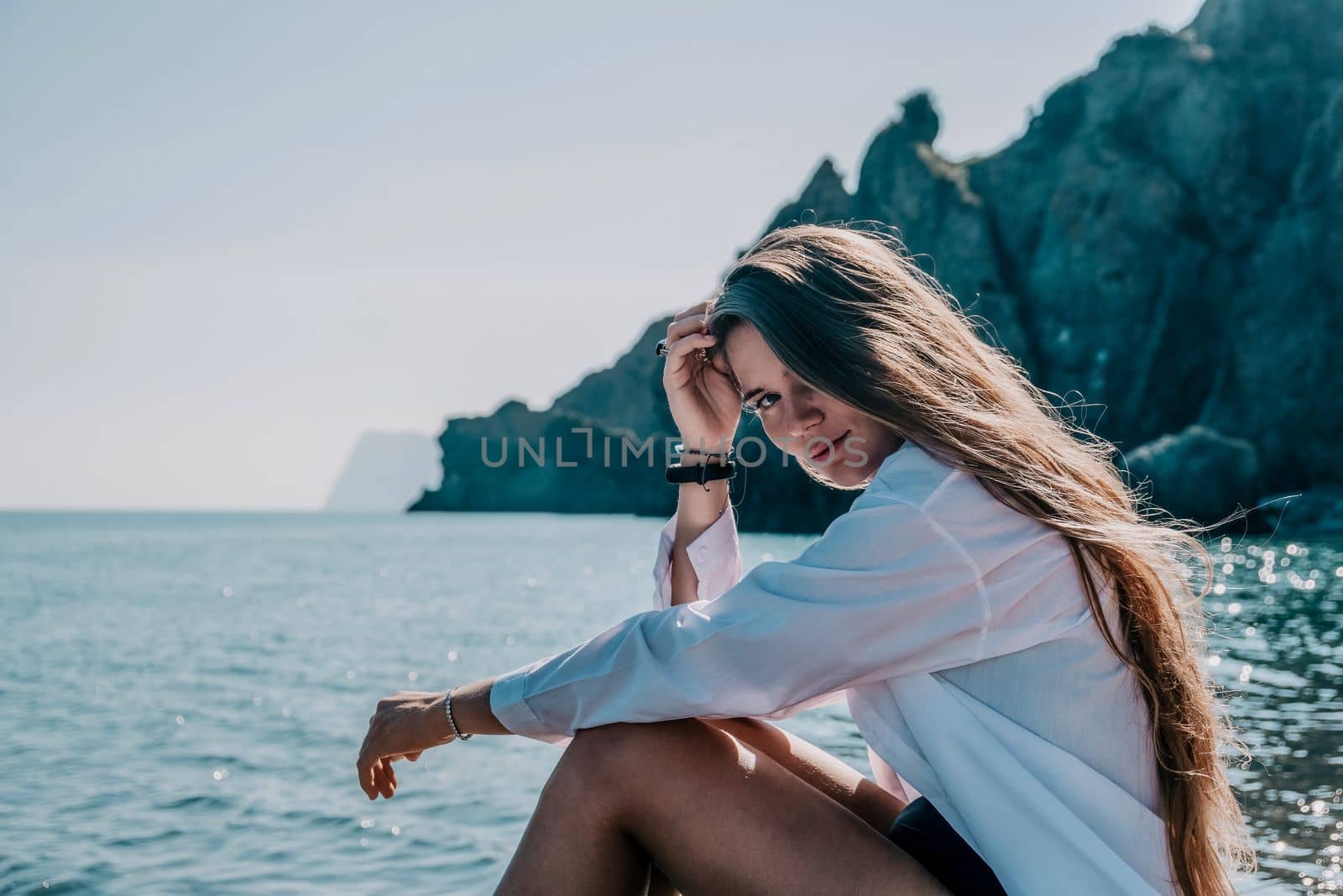 Young woman in black bikini and white shirt on Beach. Girl lying on pebble beach and enjoying sun. Happy lady in bathing suit chilling and sunbathing by turquoise sea ocean on hot summer day. Close up by panophotograph
