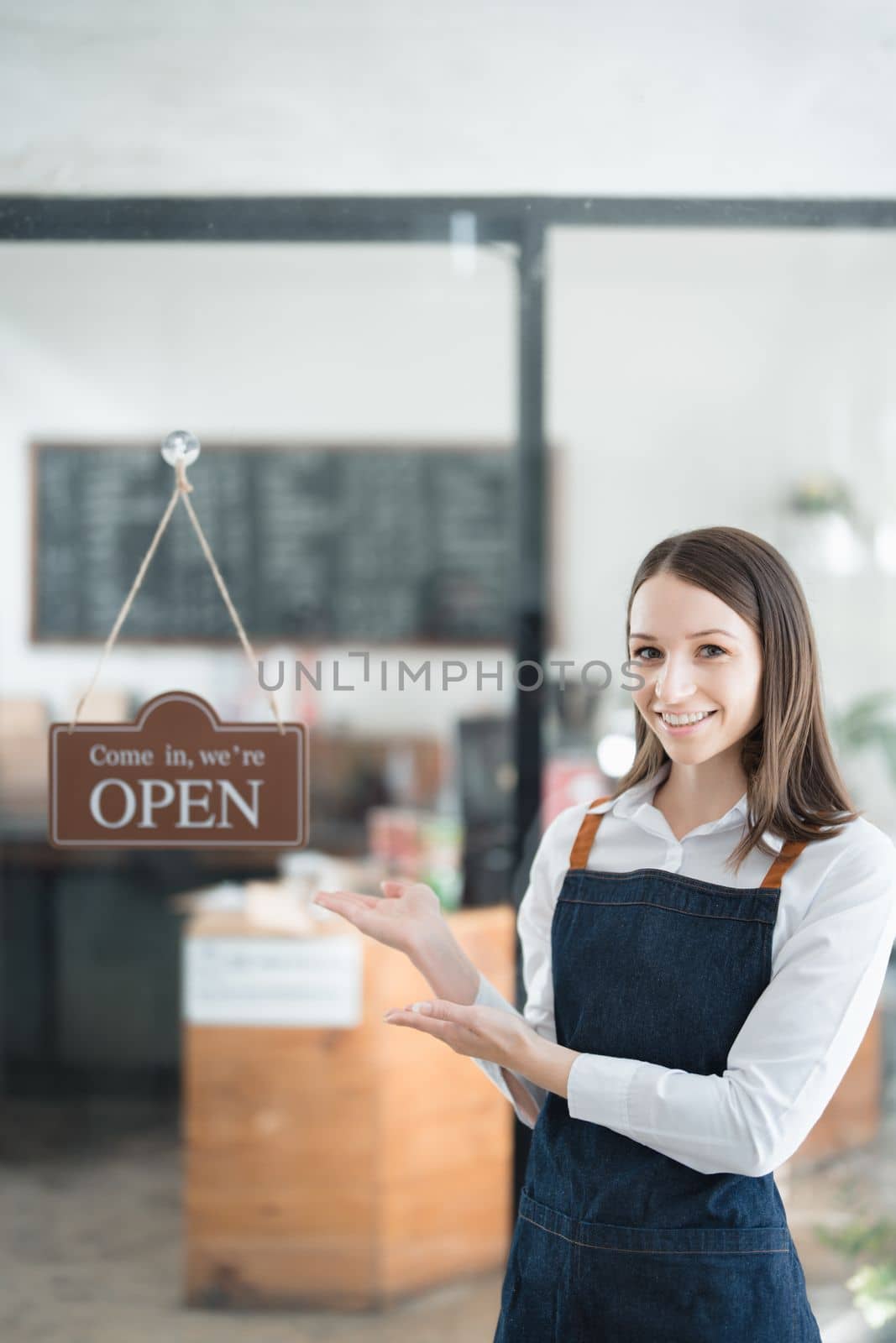 Starting and opening a small business, a young Asian woman showing a smiling face in an apron standing in front of a coffee shop bar counter. Business Owner, Restaurant, Barista, Cafe, Online SME.