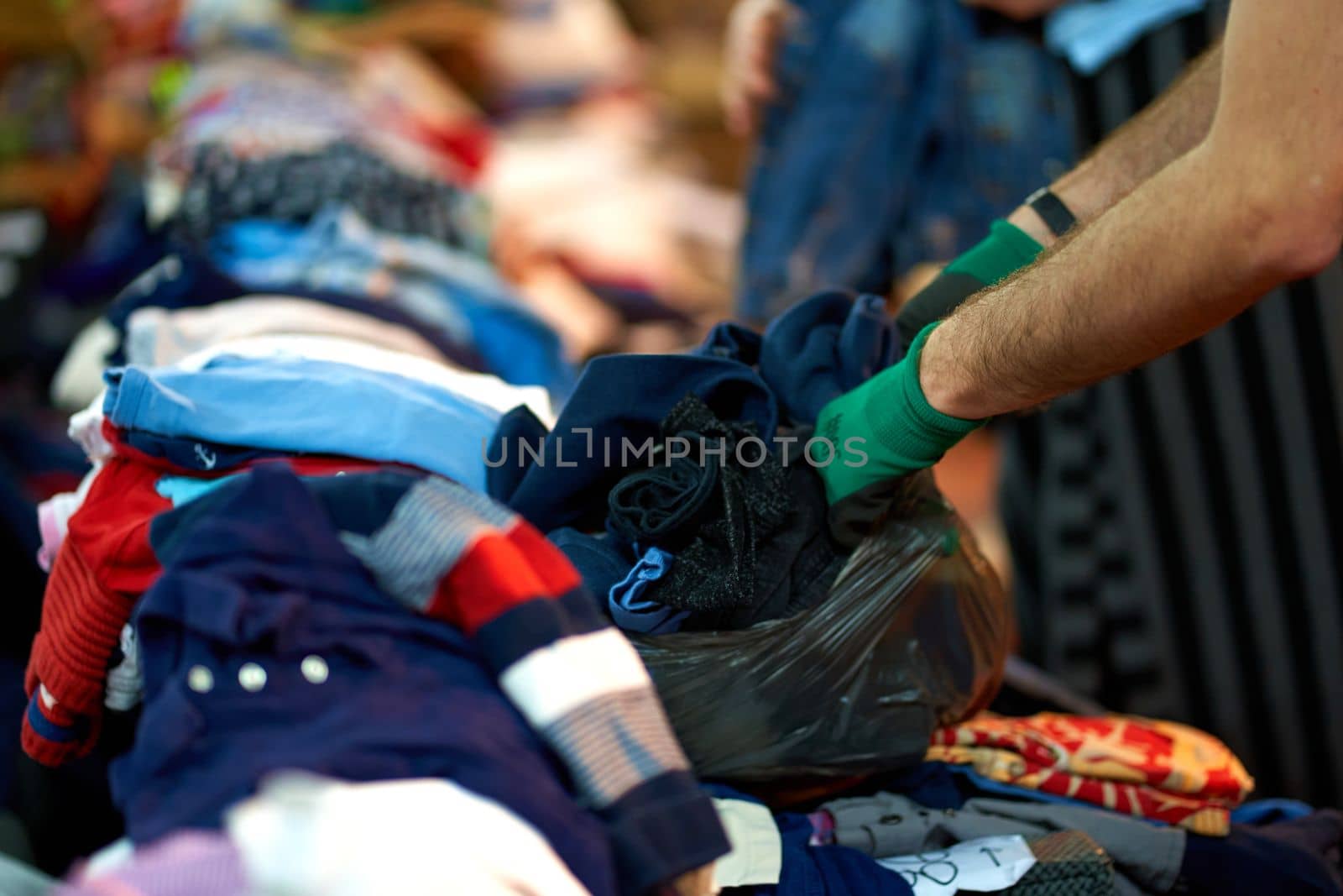 Person sorting second hand clothes by size and gender.