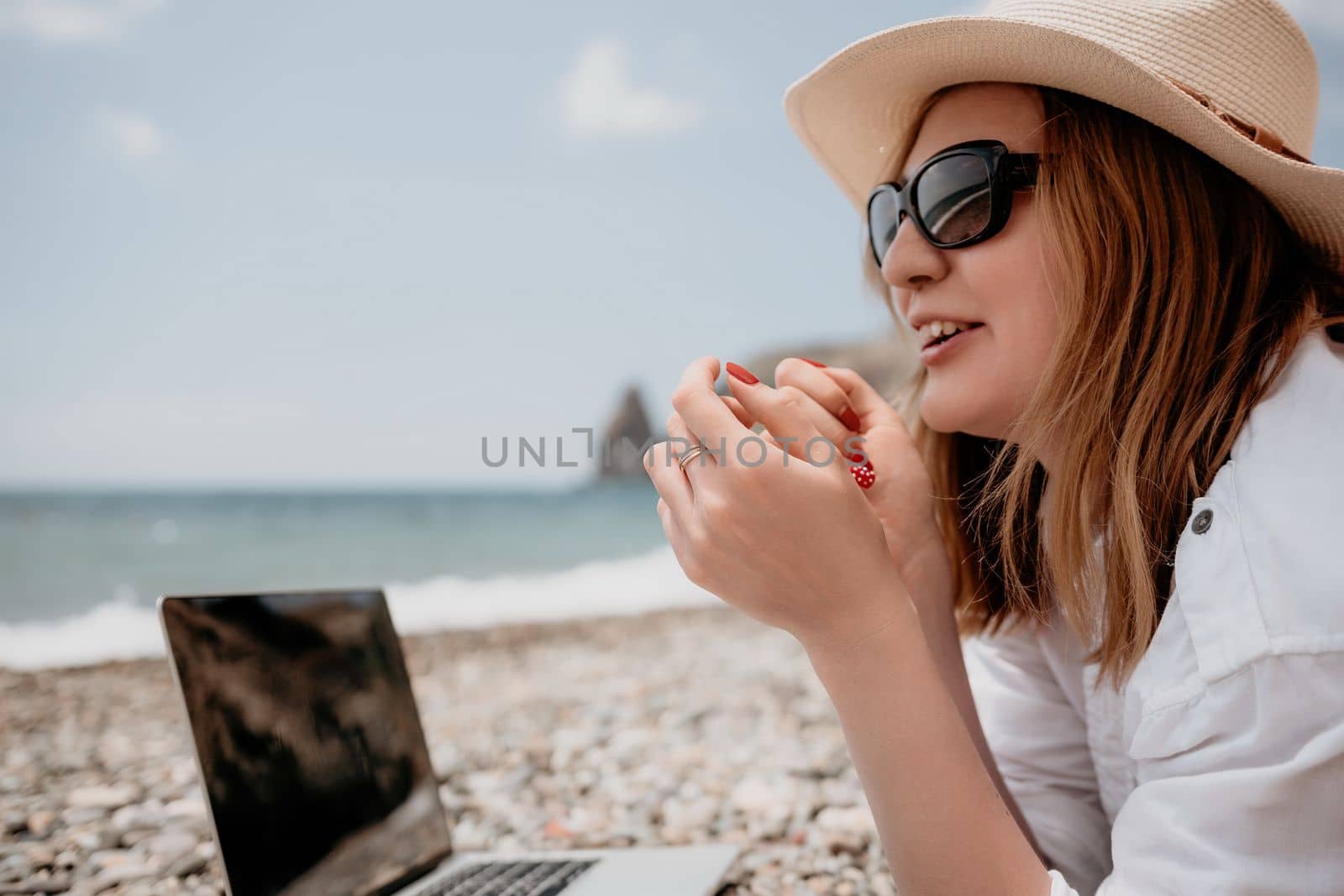Woman sea laptop. Business woman in yellow hat working on laptop by sea. Close up on hands of pretty lady typing on computer outdoors summer day. Freelance, digital nomad, travel and holidays concept