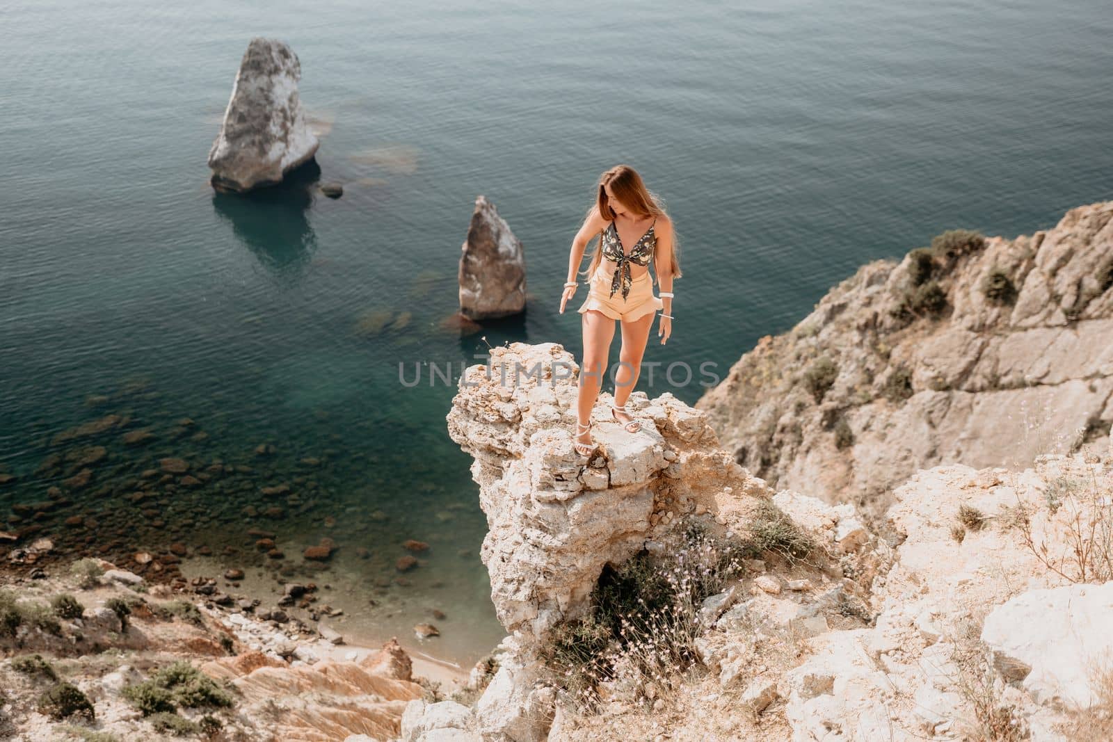 Woman travel sea. Happy tourist enjoy taking picture outdoors for memories. Woman traveler looks at the edge of the cliff on the sea bay of mountains, sharing travel adventure journey by panophotograph