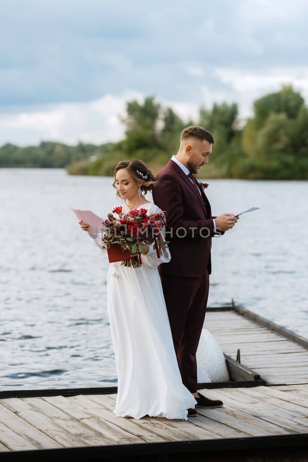 the first meeting of the bride and groom in wedding dresses on the pier near the water