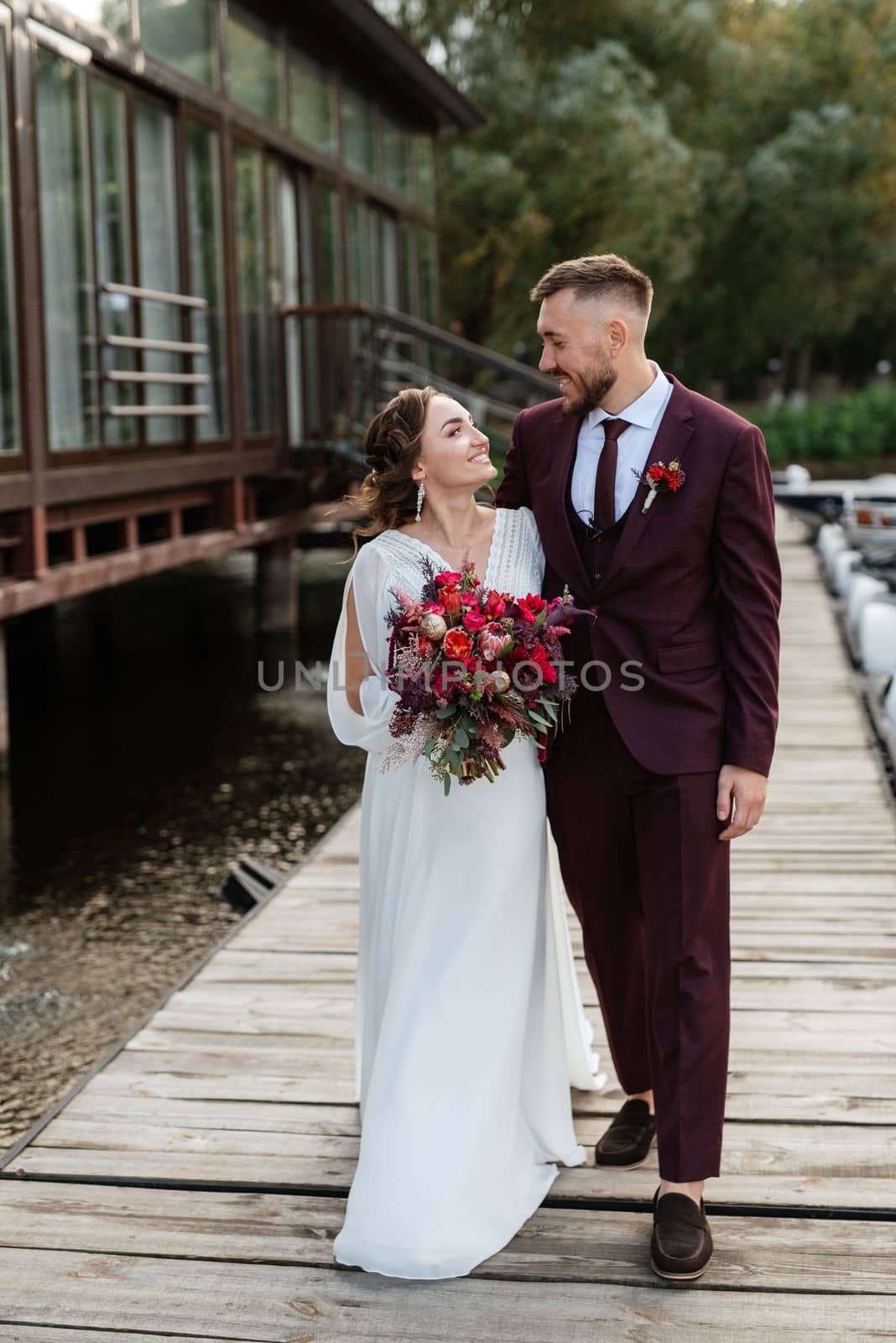 the first meeting of the bride and groom in wedding dresses on the pier near the water