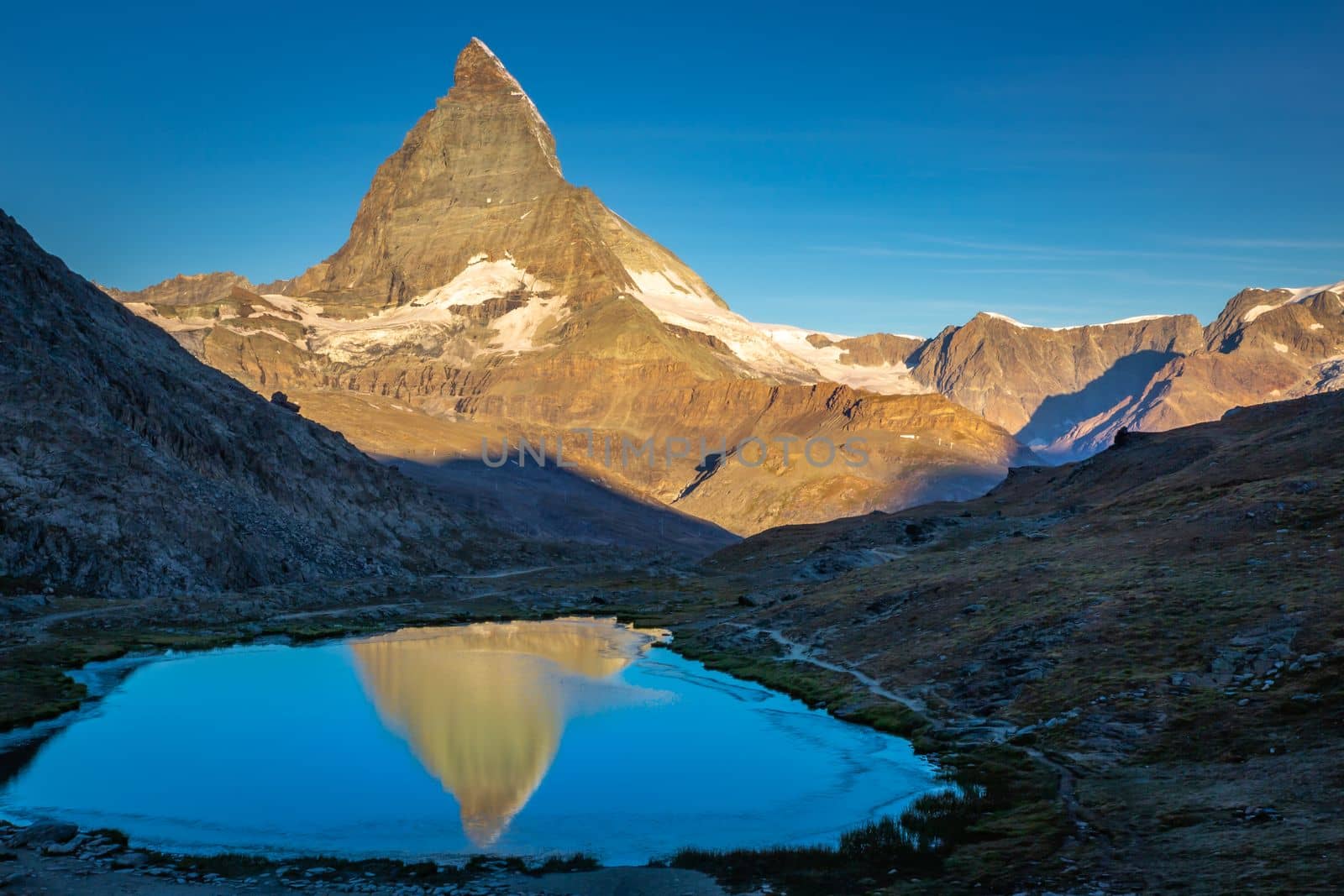 Reflection of the Matterhorn on blue and placid lake at sunrise, Swiss Alps, Zermatt, Switzerland