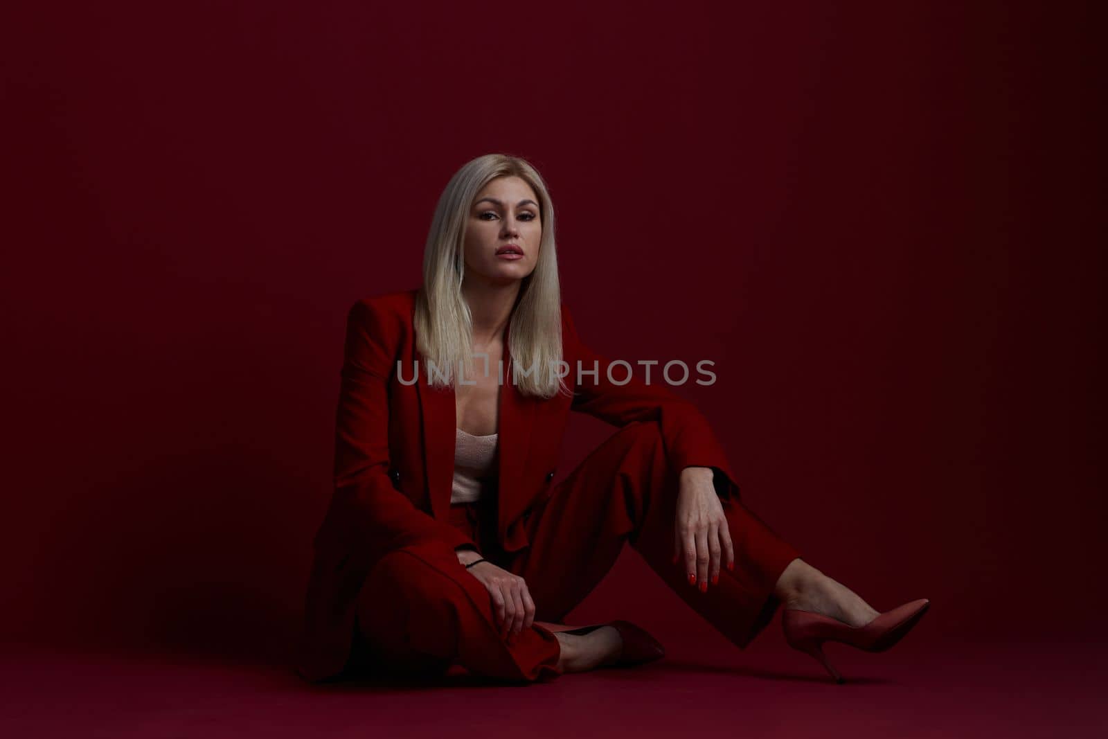 Portrait of a blonde woman in red dress on a red background