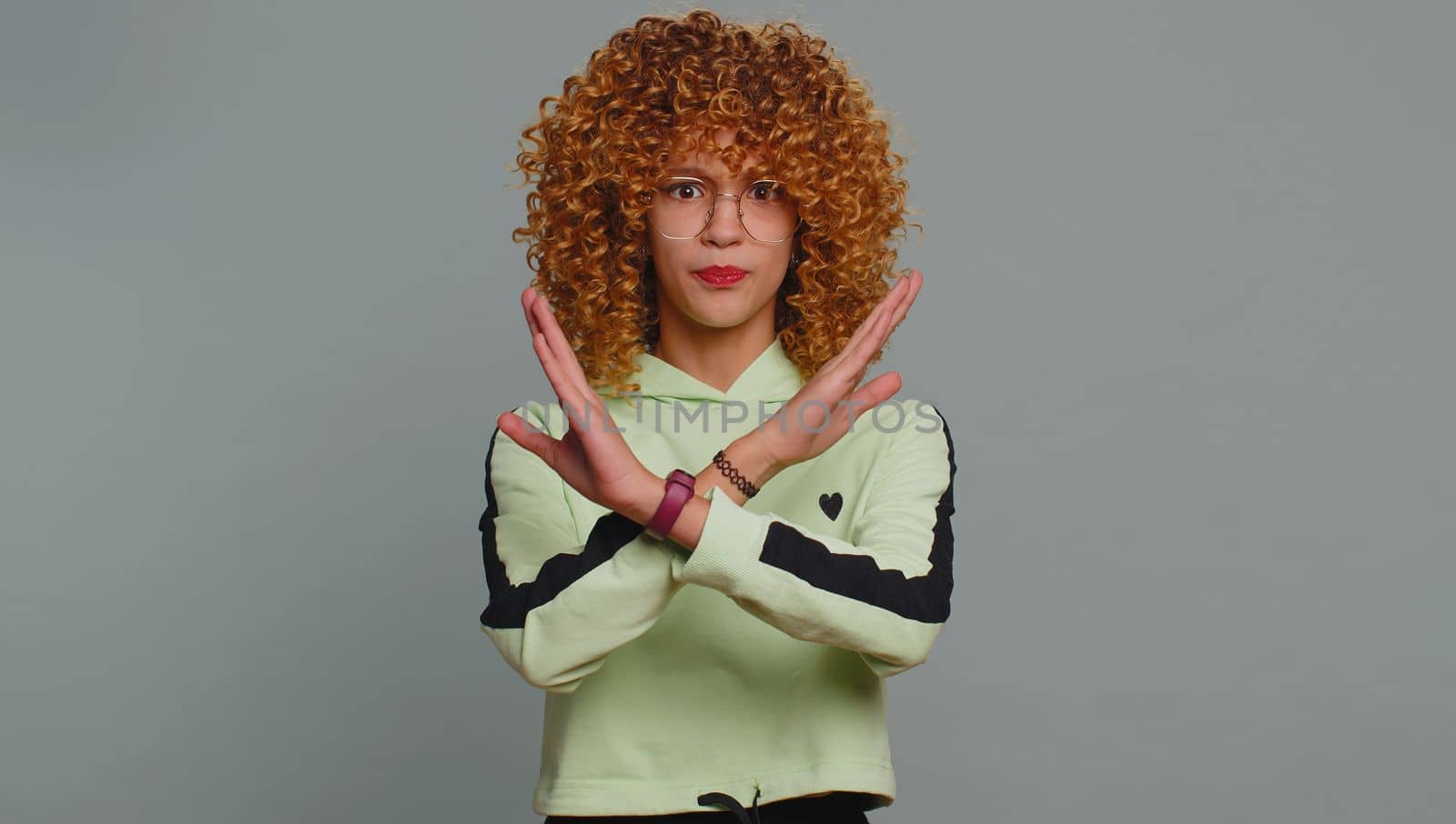 Stop gesture. Angry young child girl kid say No hold palm folded crossed hands, warning of finish, prohibited access, declining communication, body language, danger. Teenager children with curly hair