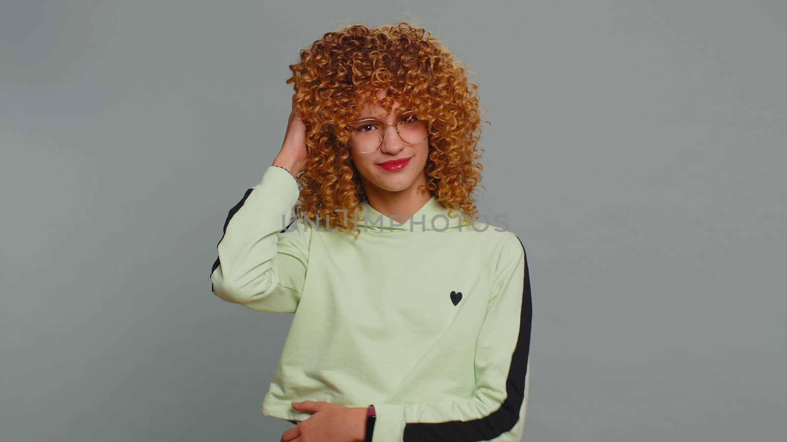 I dont know what to say. Confused young teenager school girl feeling embarrassed about ambiguous question having doubts no idea, being clueless and uncertain. Curly hair child kid on gray background