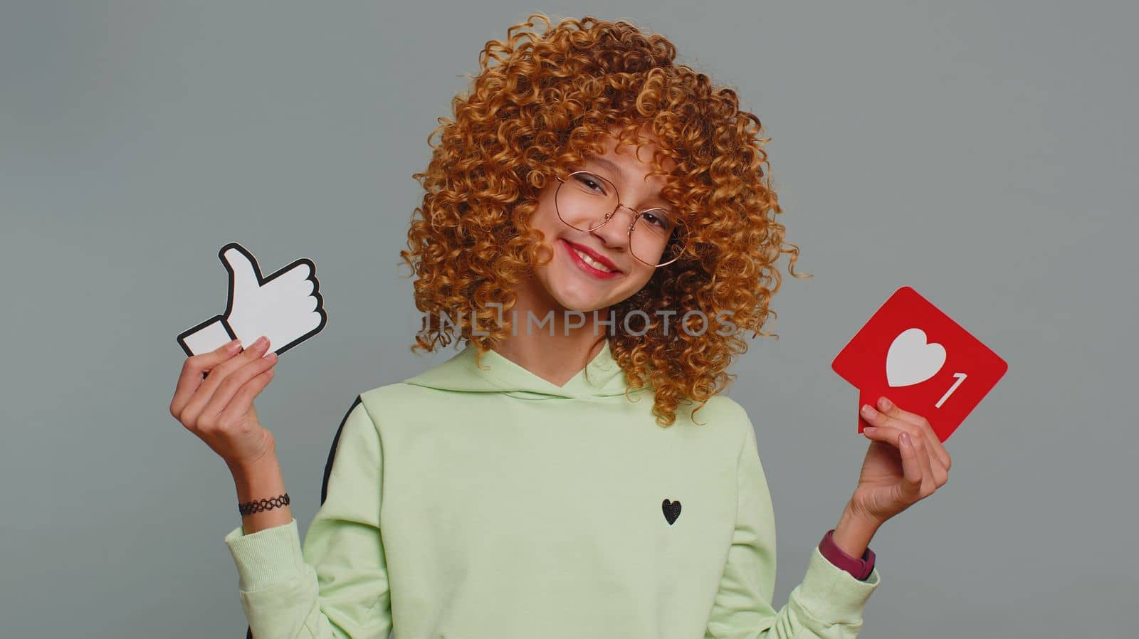 Like. Happy young child girl kid looking approvingly at camera showing thumbs up, like sign banner social media logo, something good, positive feedback. Teenager children isolated on gray background