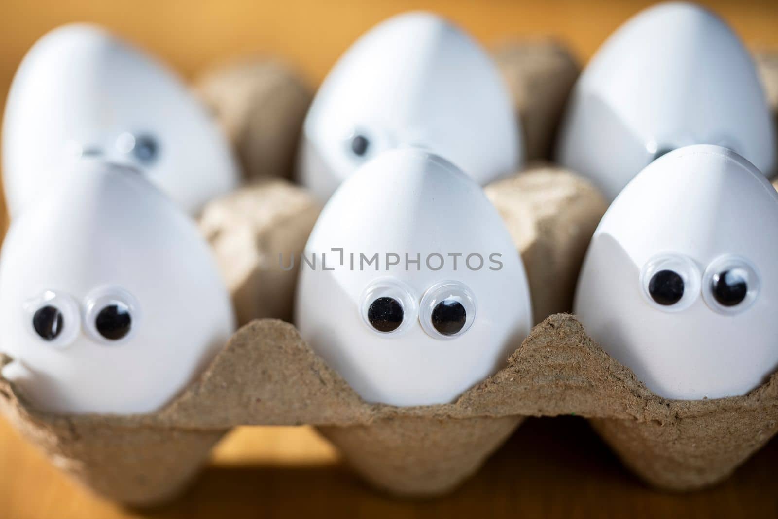 Funny faces on white eggs in carton box with organic chicken eggs on kitchen table closeup big animation eyes. humor, food and easter holiday concept. close up