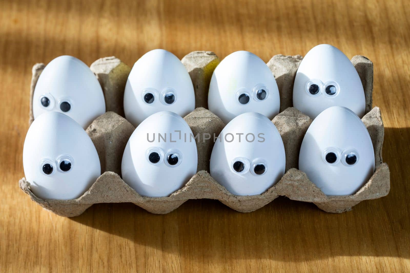 Funny faces on white eggs in carton box with organic chicken eggs on kitchen table closeup big animation eyes. humor, food and easter holiday concept. close up