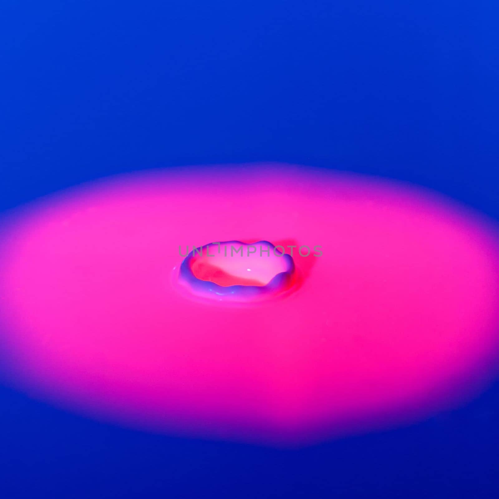A drop falls into a thick liquid with a blue-pink background. Abstract colorful background. by Yurich32