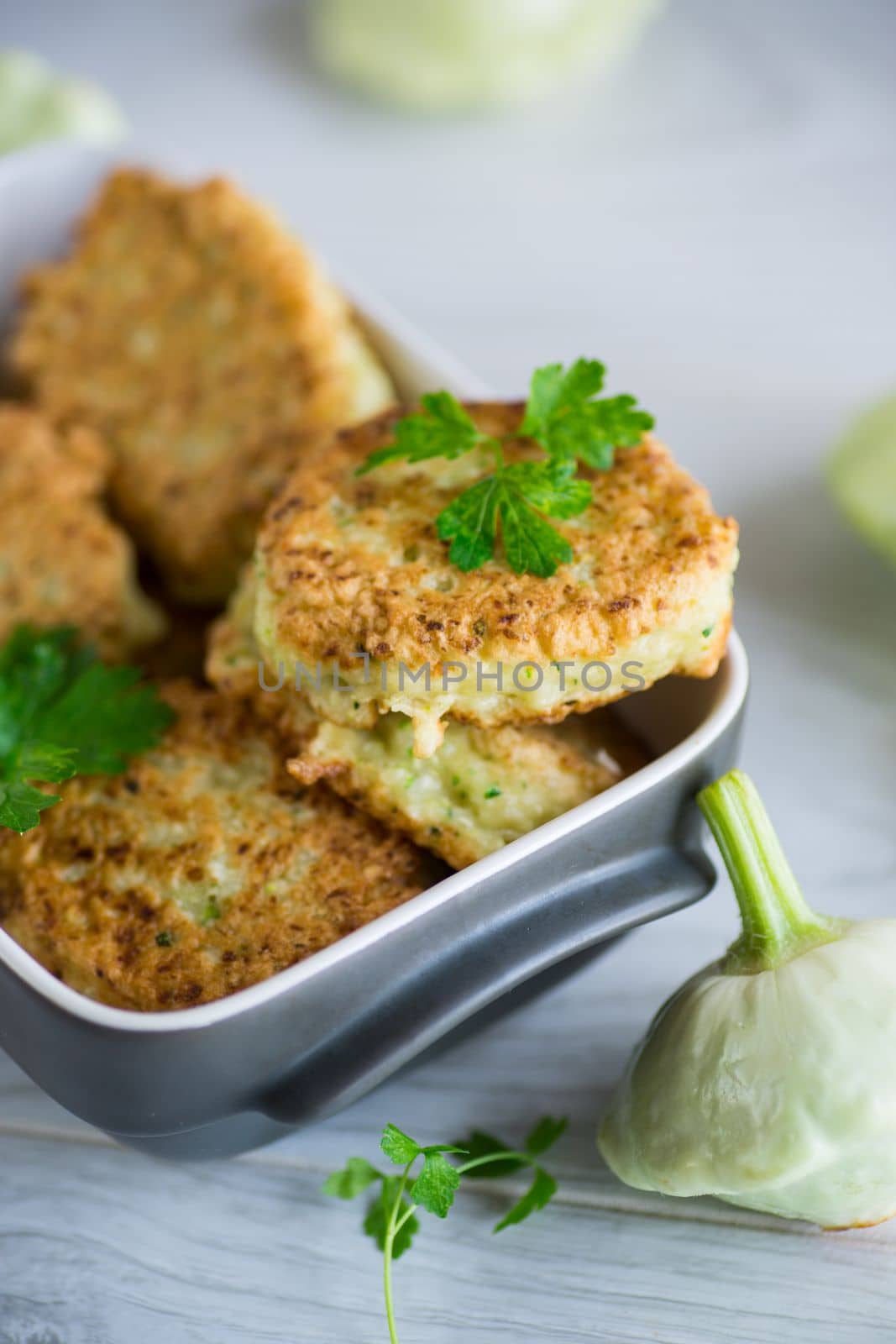 vegetable fried squash and zucchini cutlets in a ceramic form on a light wooden table