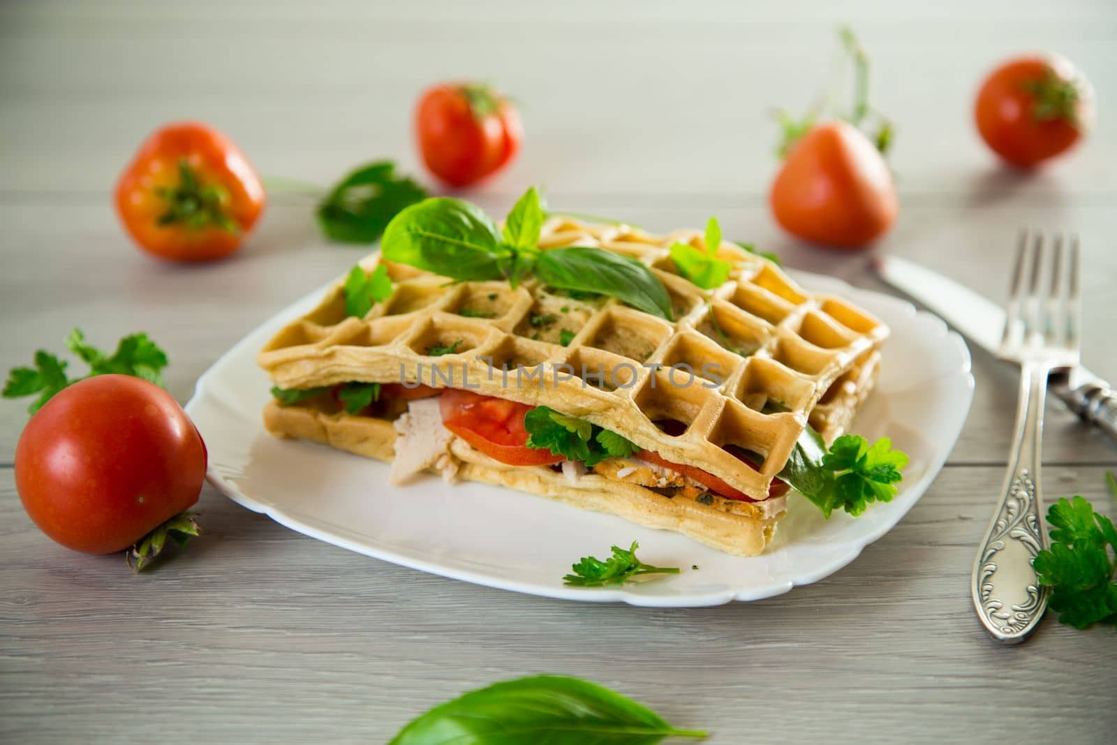 Sandwich of two egg omelettes with bacon and tomatoes inside, waffle shaped.