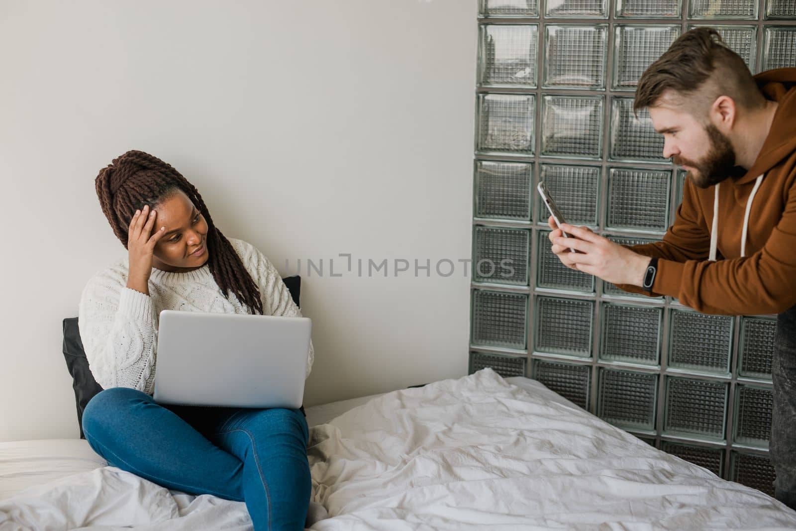 Cheerful african american woman blogger with laptop while guy making photo for blog or social media. Man taking picture of girl when she writing post on social media vlog by Satura86