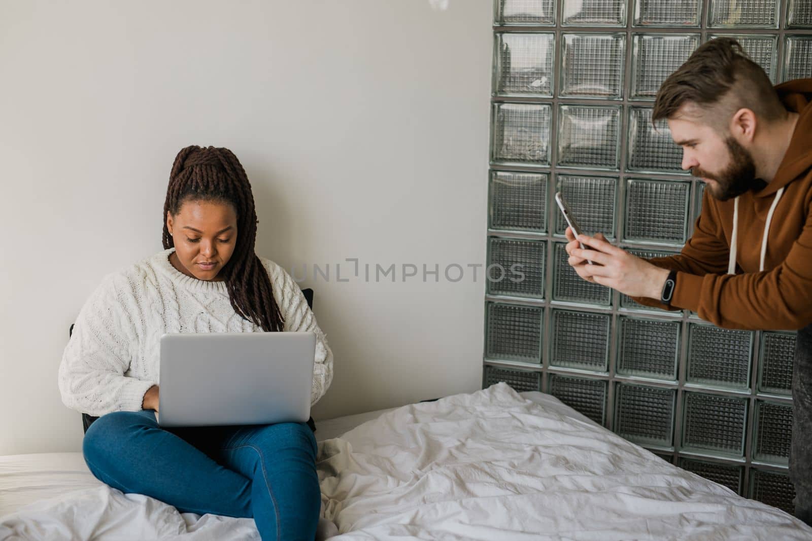 Cheerful african american woman blogger with laptop while guy making photo for blog or social media. Man taking picture girl when she writing post on social media vlog