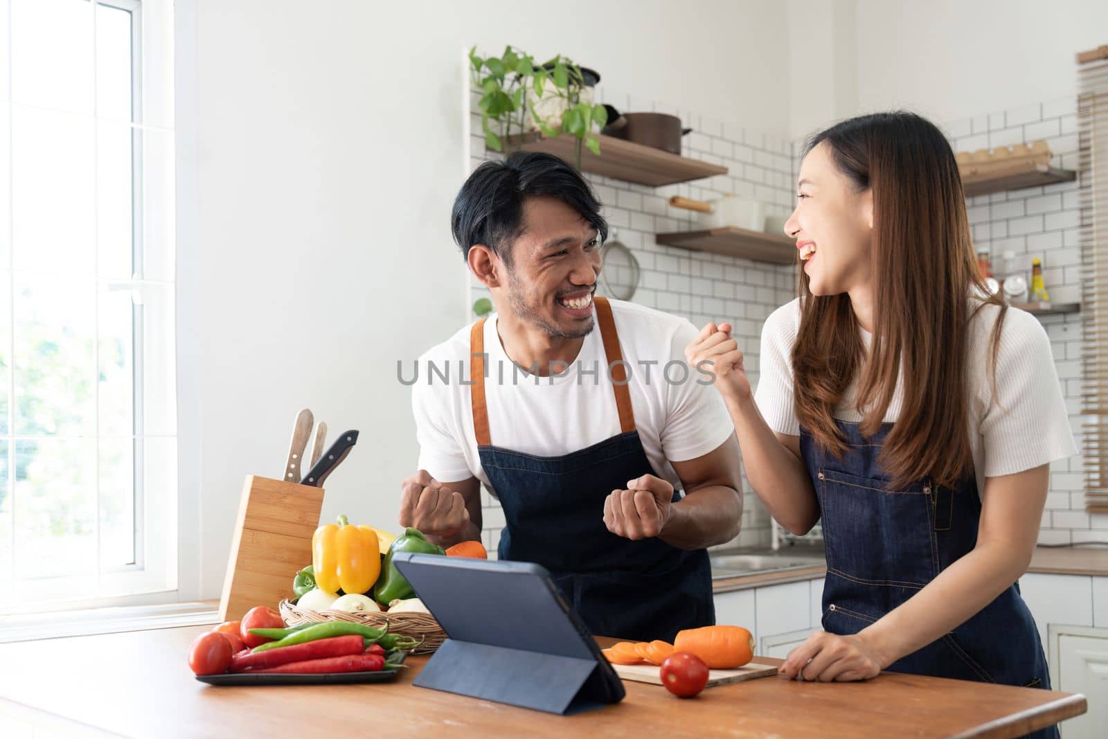 Happy couple preparing food together in kitchen at home ready to cook together by nateemee