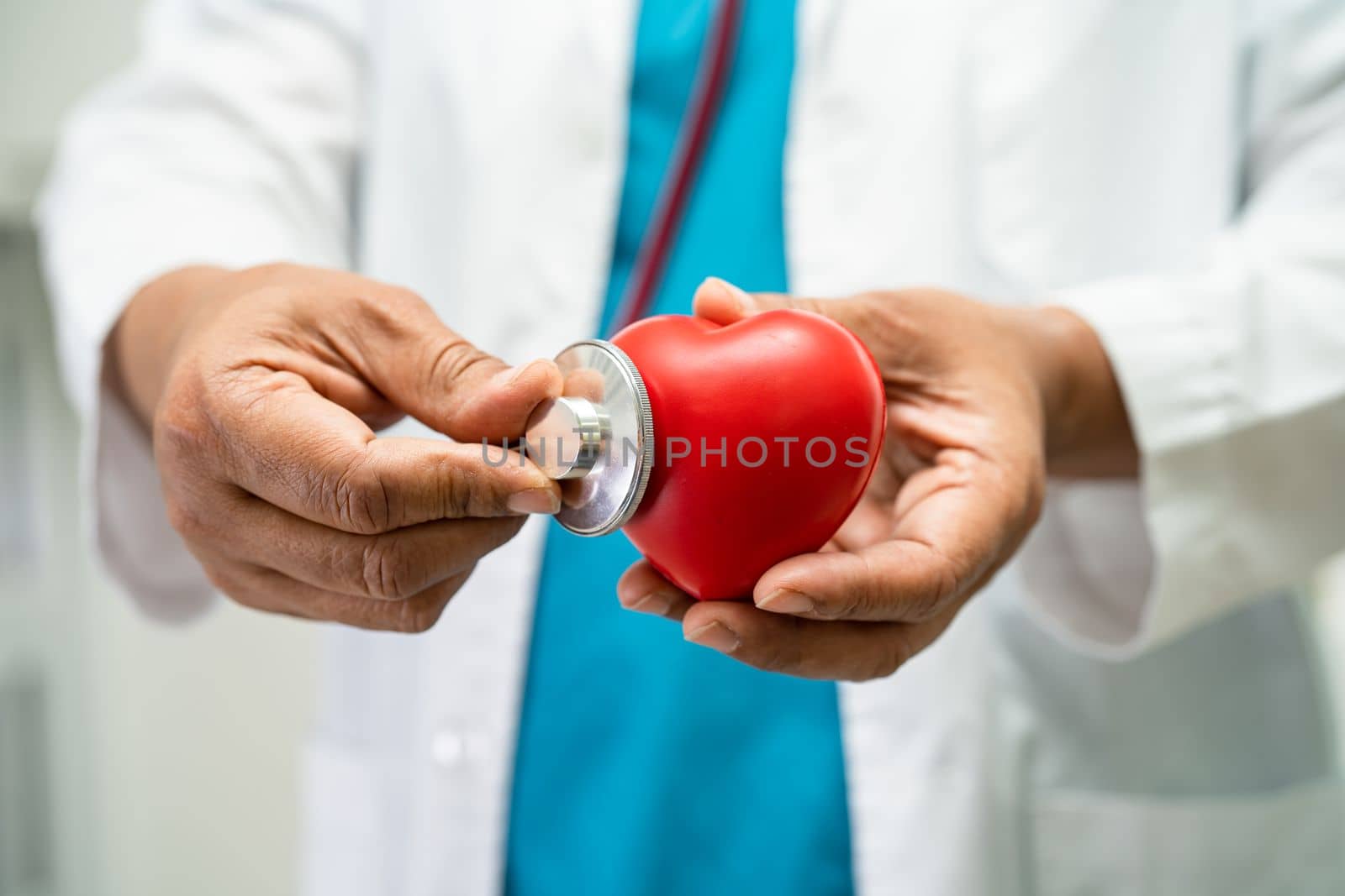 Doctor holding a red heart in hospital ward, healthy strong medical concept.