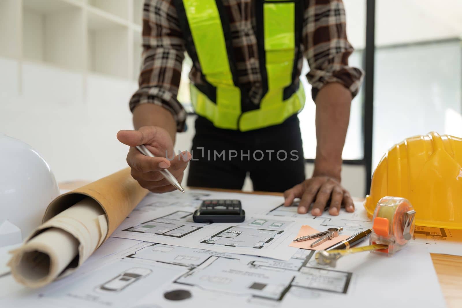 Architect or engineer working with blueprints for architectural plan, engineer sketching a construction project, green energy concept.
